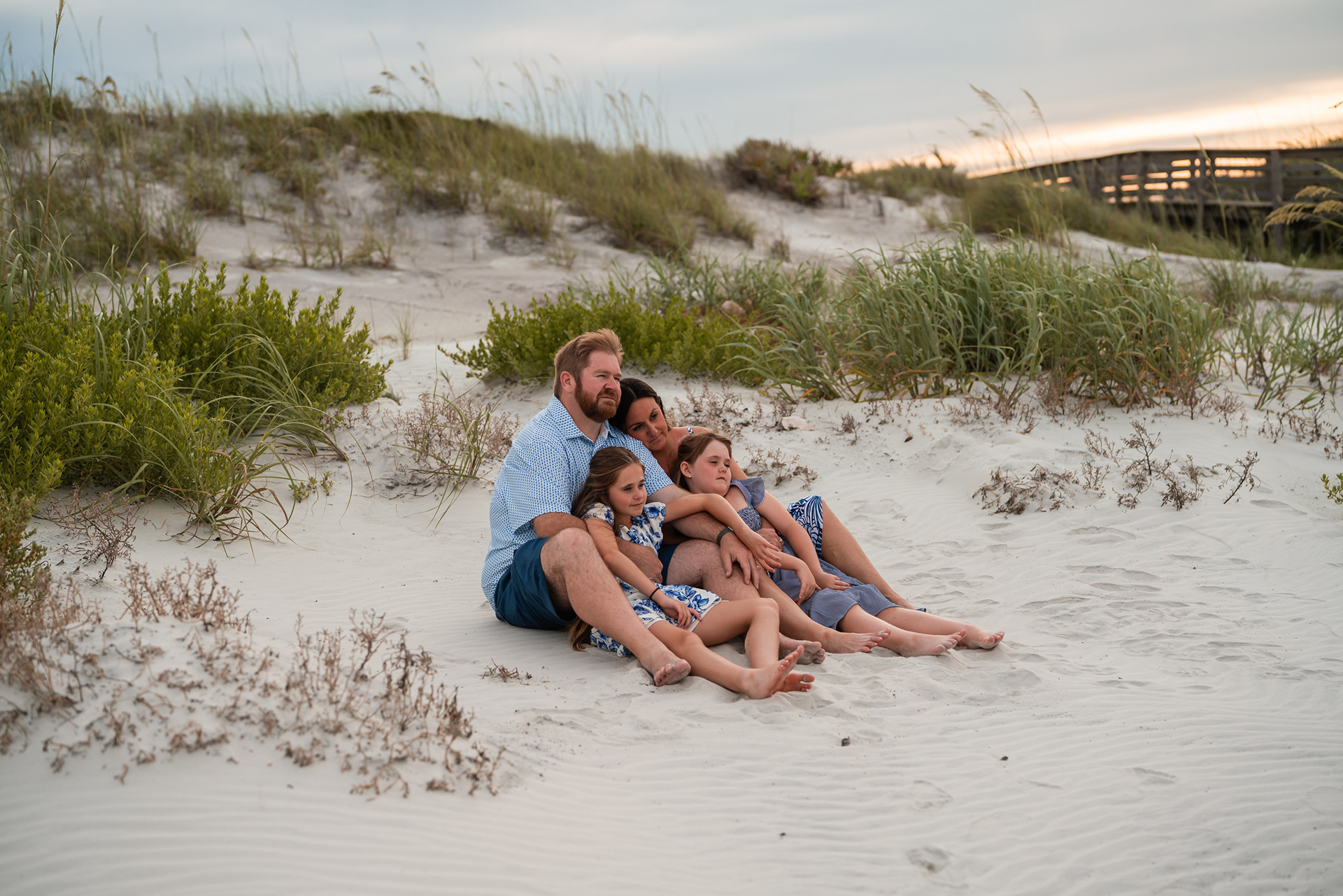 Family sitting together in the dunes during a relaxed beach photo session in Ponce Inlet.