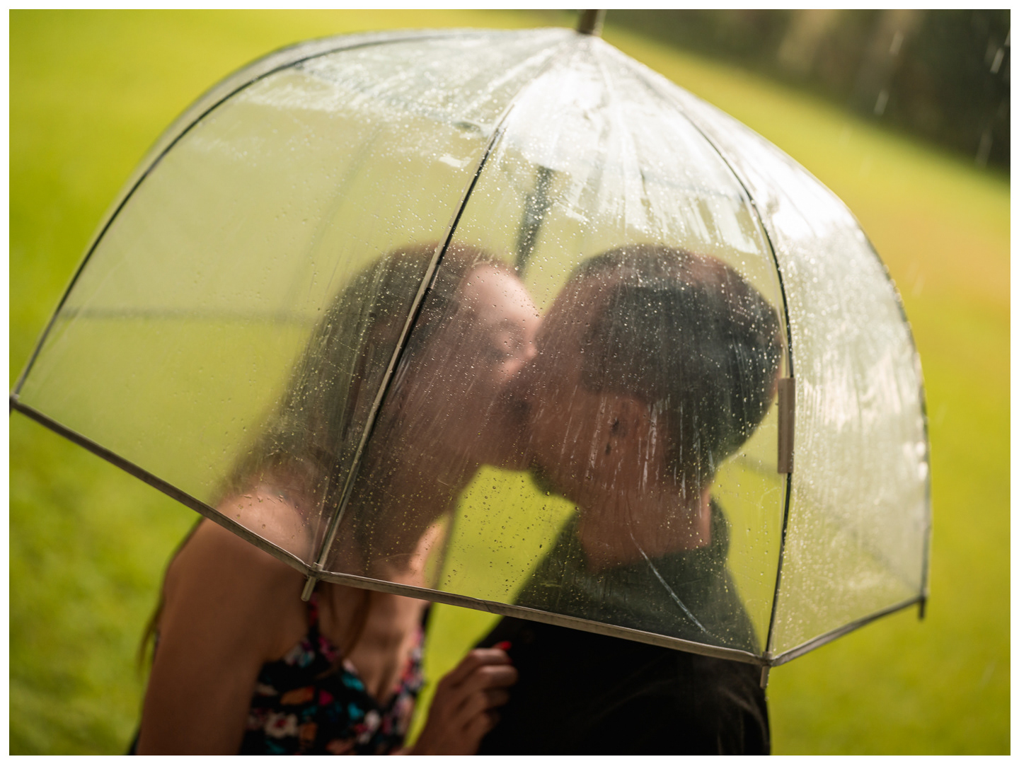 Couple kissing behind a rain-covered clear umbrella at Washington Oaks Gardens State Park.