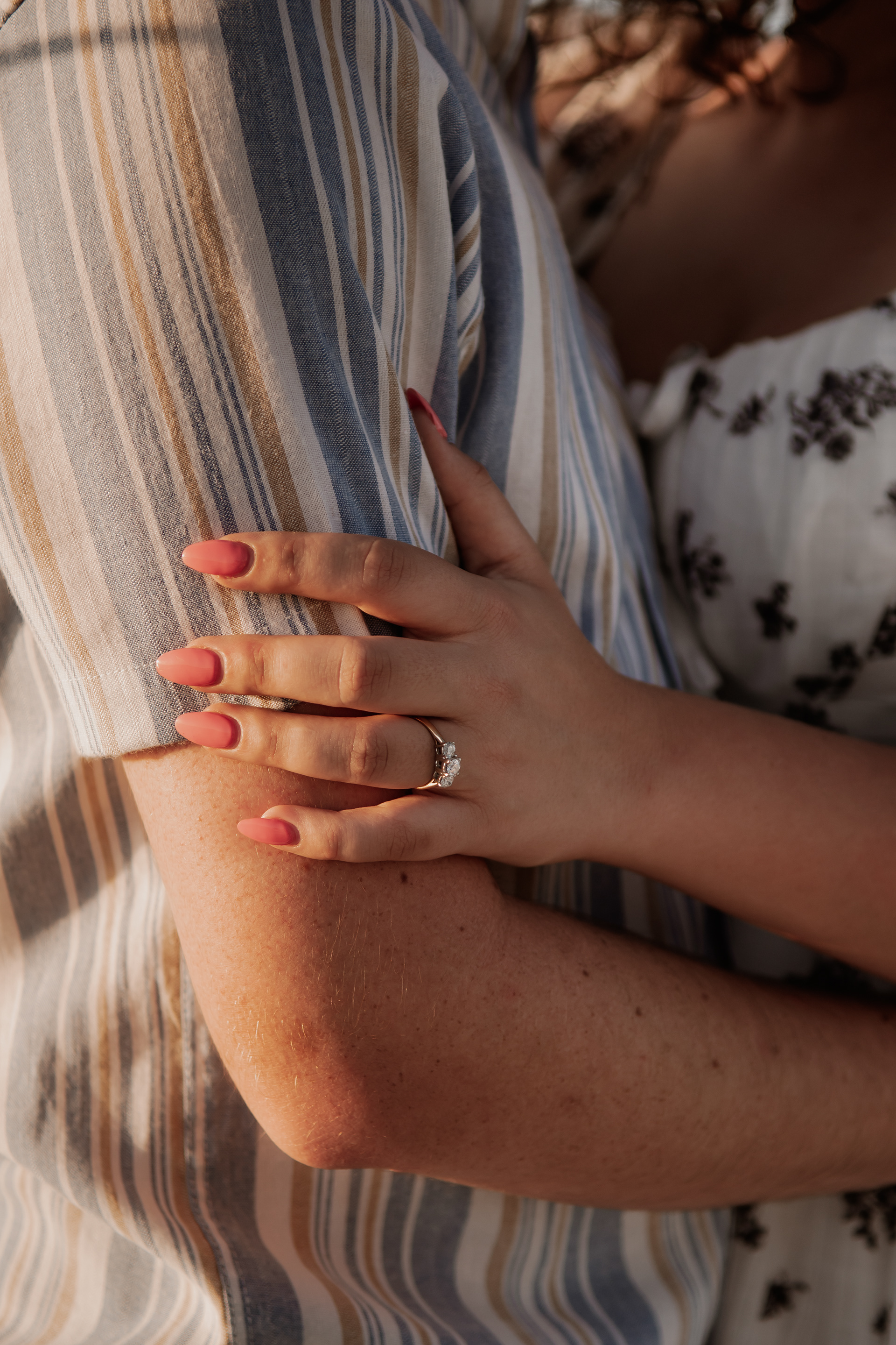 Engagement ring detail photo with couple embracing during Daytona Beach sailboat session