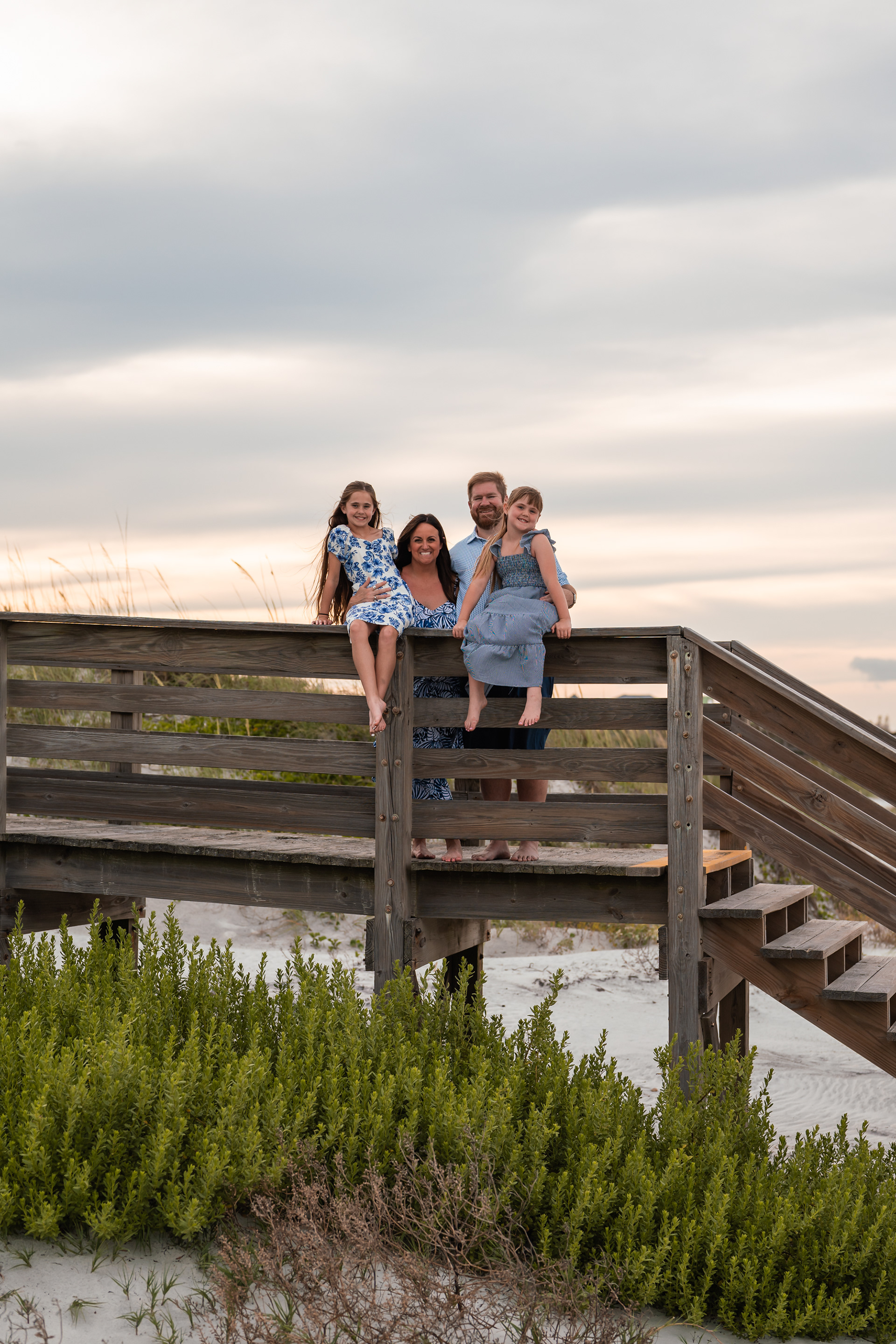 Family sitting on the wooden beach access stairs during a family photo session in Ponce Inlet.