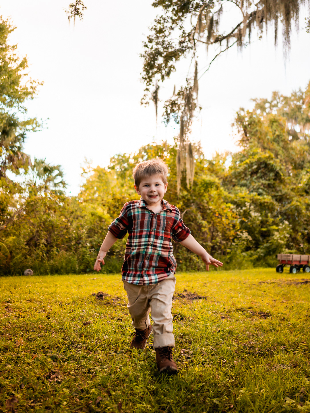 Young boy running toward the camera in golden light during family photos in New Smyrna Beach backyard.