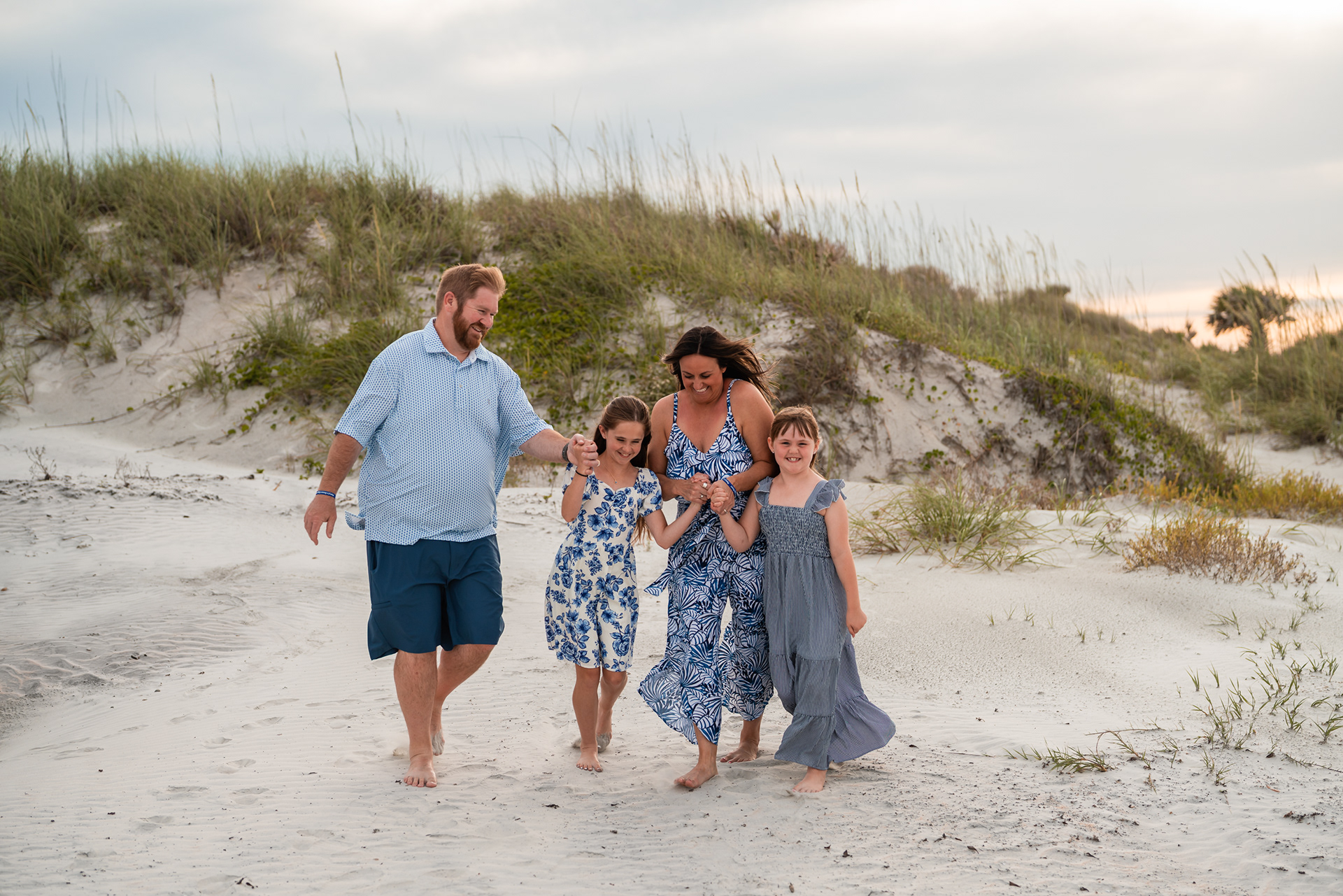 Family laughing and walking through the sand during a relaxed beach photo session in Ponce Inlet.