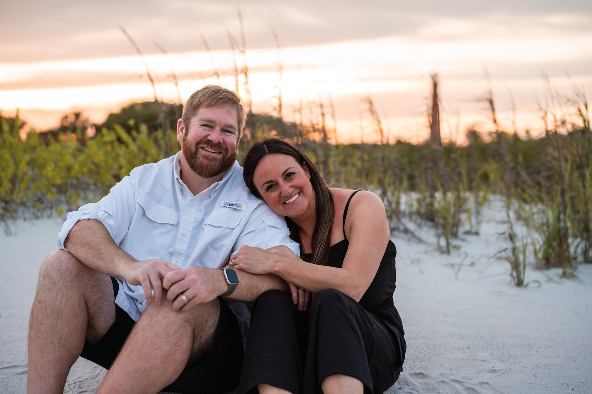 Couple sitting together in the sand during a family photography session at Ponce Inlet Beach.