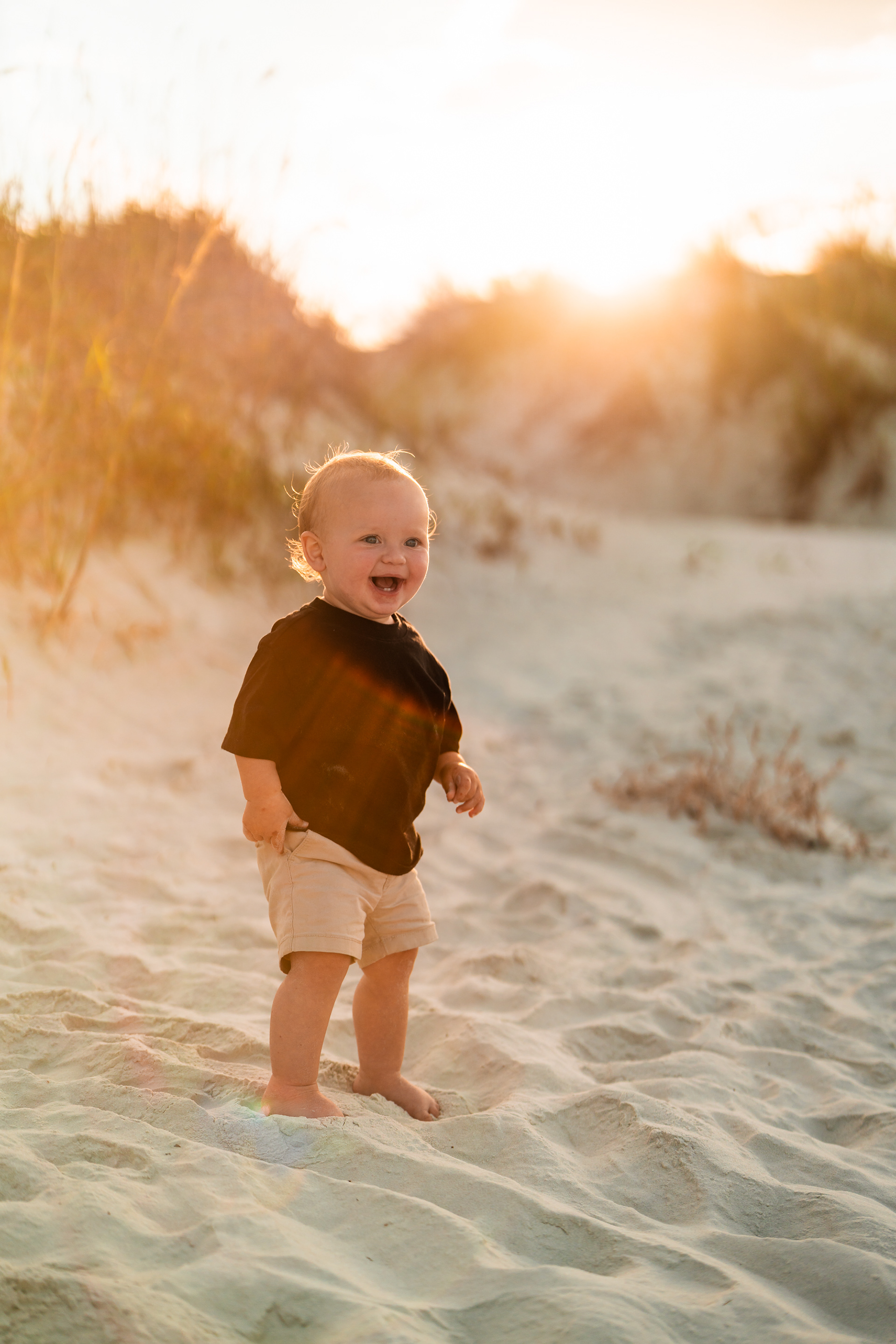 Toddler walking in the sand during a sunset family photo session at Ponce Inlet Jetty Beach.