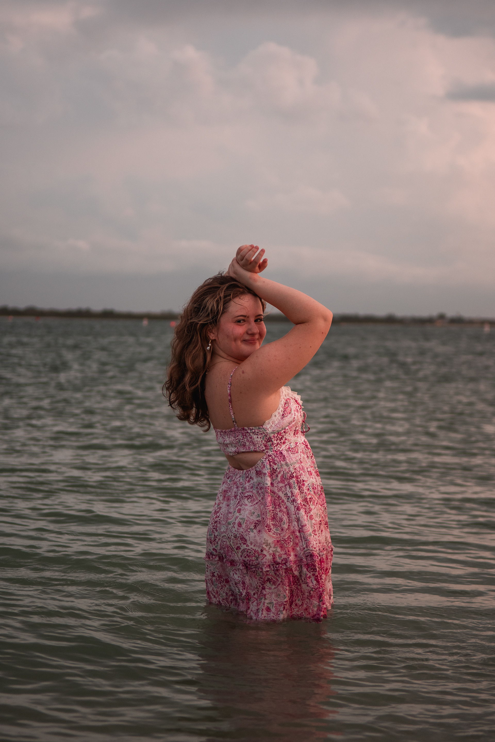 Ponce Inlet senior photo session, Nelly in pink floral dress posing in the inlet water at sunset