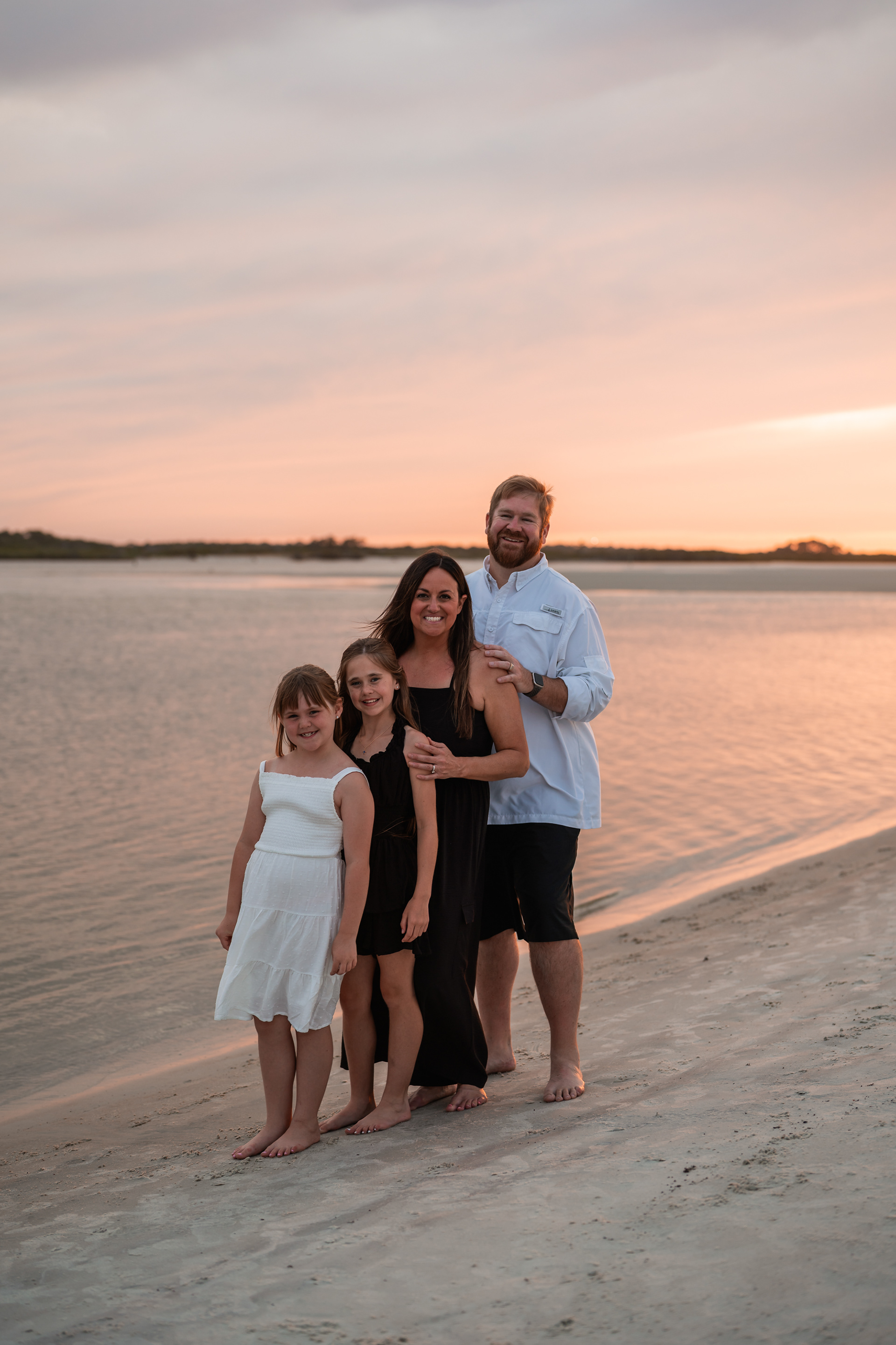 Family standing together near the shoreline during a beach photo session in Ponce Inlet, Florida.