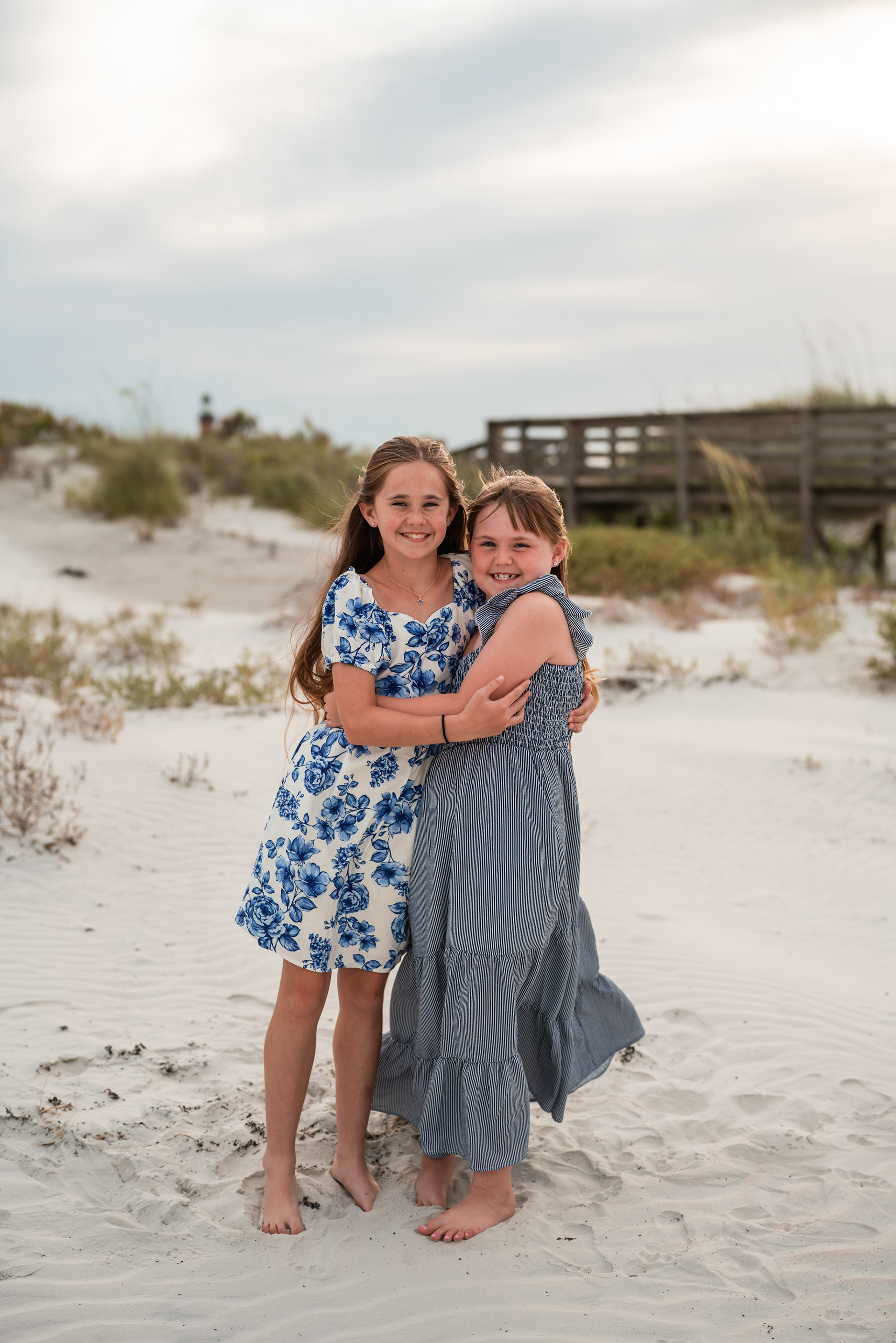 Two sisters standing together in the sand during a family photo session at Ponce Inlet Beach.