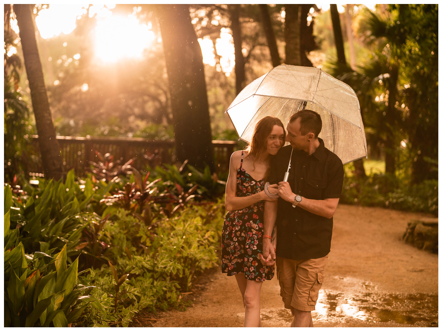 Couple walking side by side beneath an umbrella on a wet path at Washington Oaks Gardens State Park.