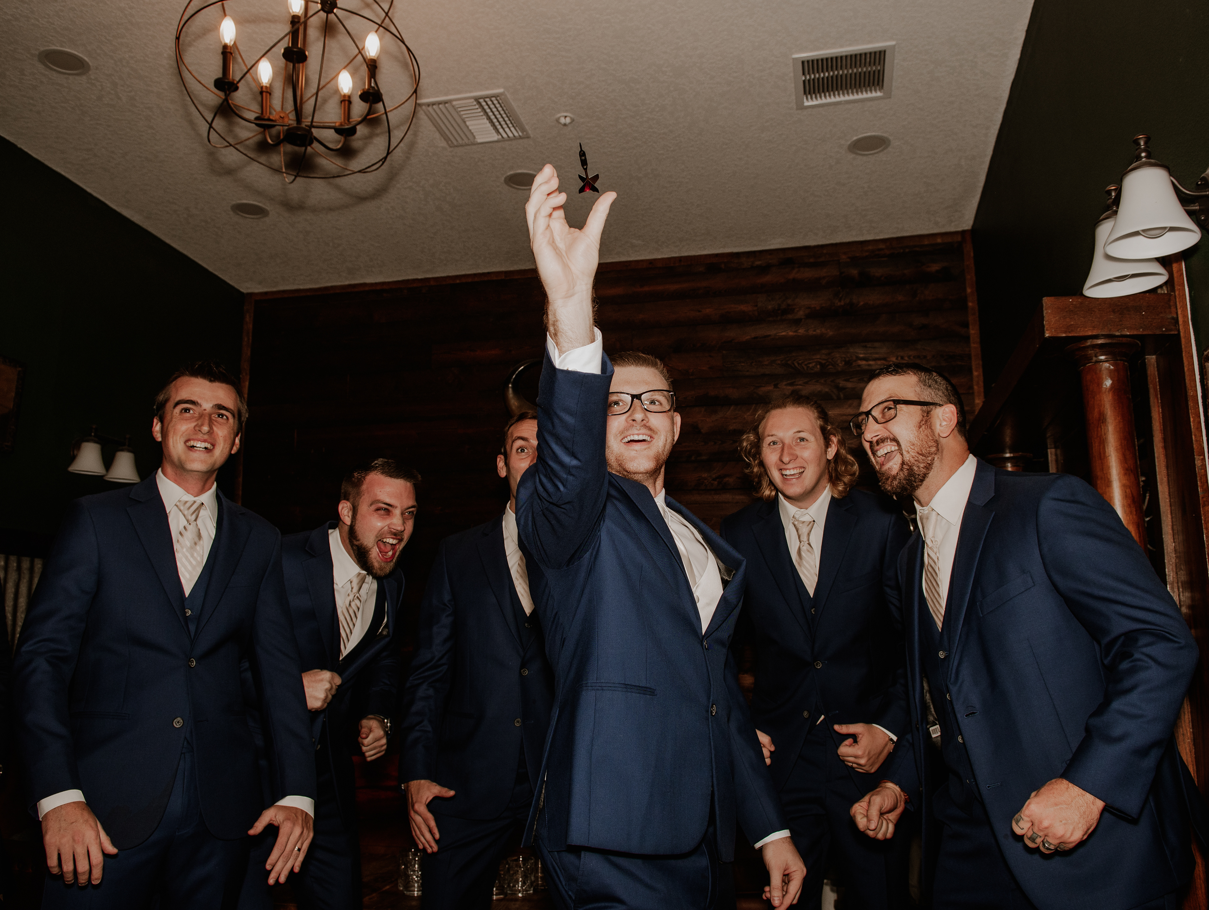 Groom and groomsmen in navy suits celebrating before wedding ceremony, candid group photo at Florida wedding venue.