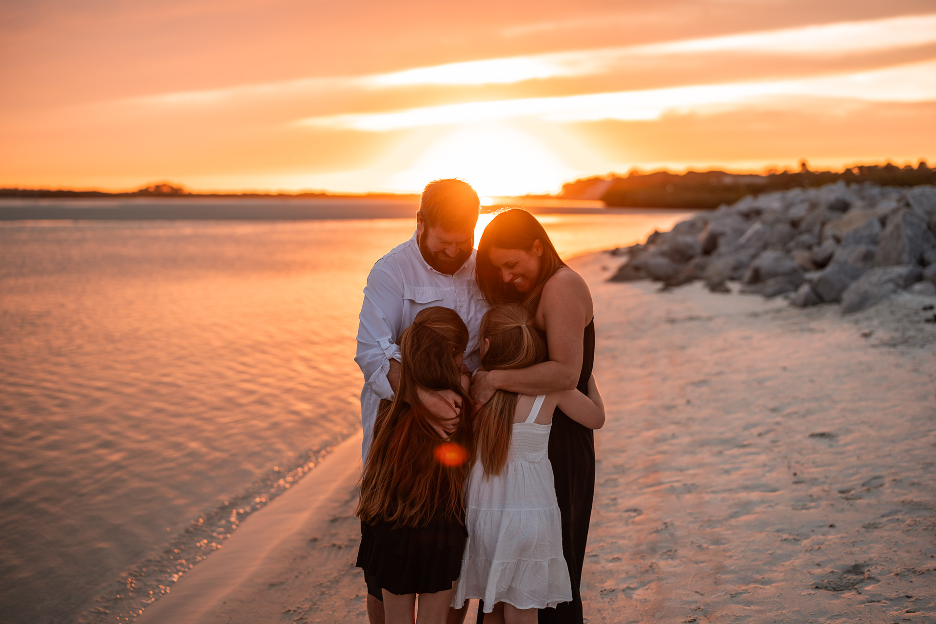 Parents hugging their children during a sunset family photography session at Ponce Inlet Beach.