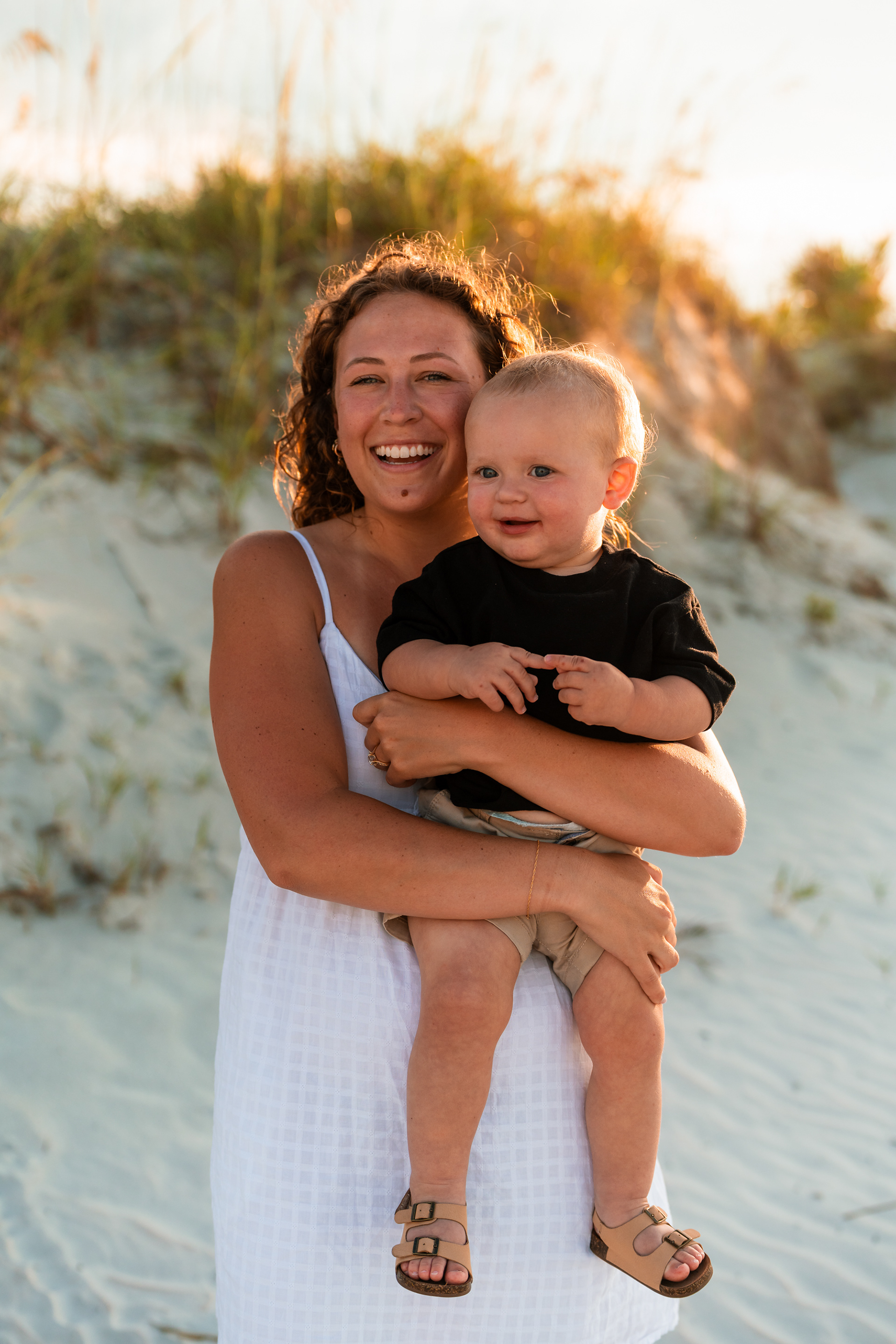 Smiling portrait of a woman holding a toddler during a Ponce Inlet beach family session.