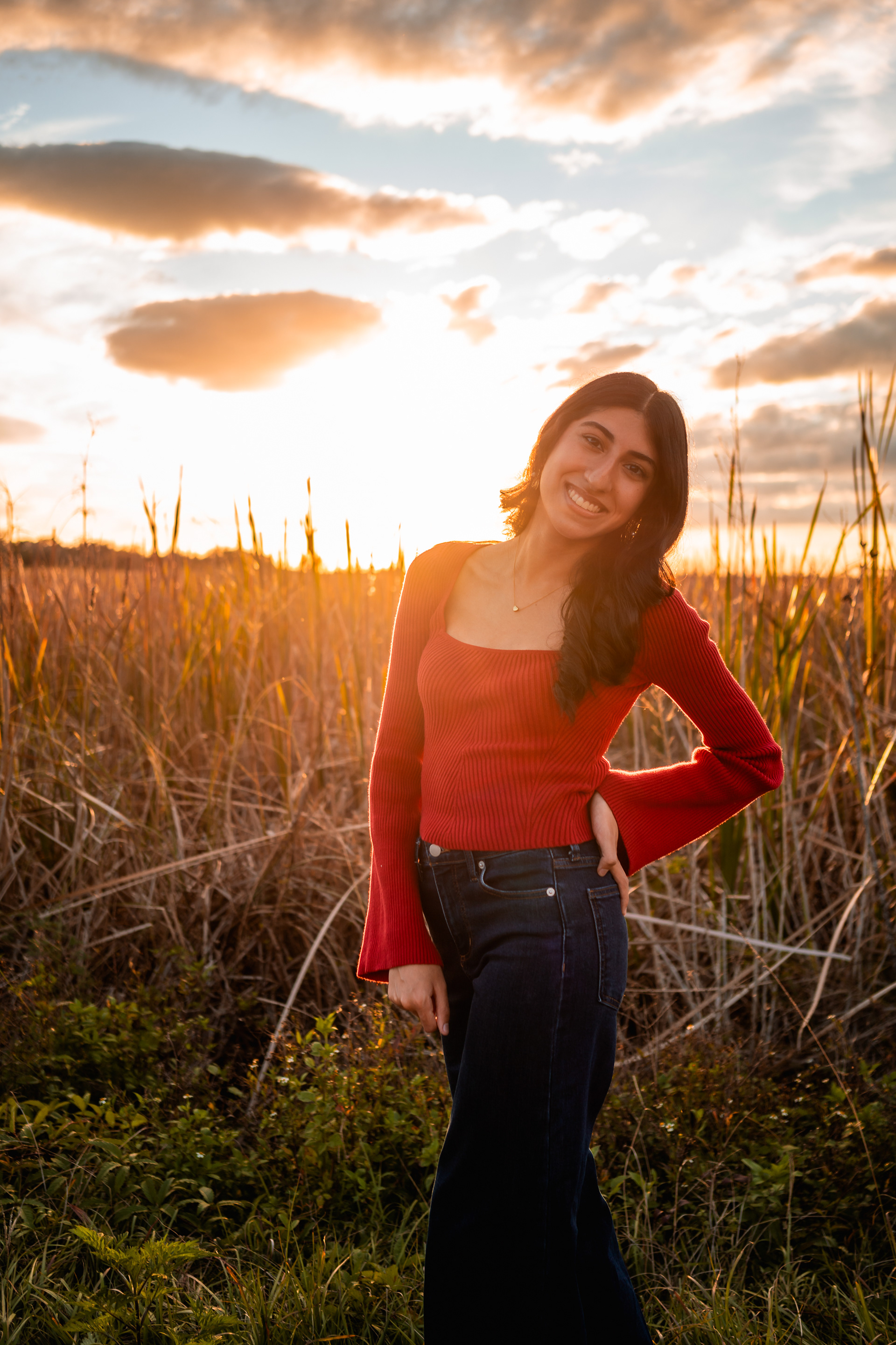Ahaana posing in tall grass for senior photos near DeLeon Springs