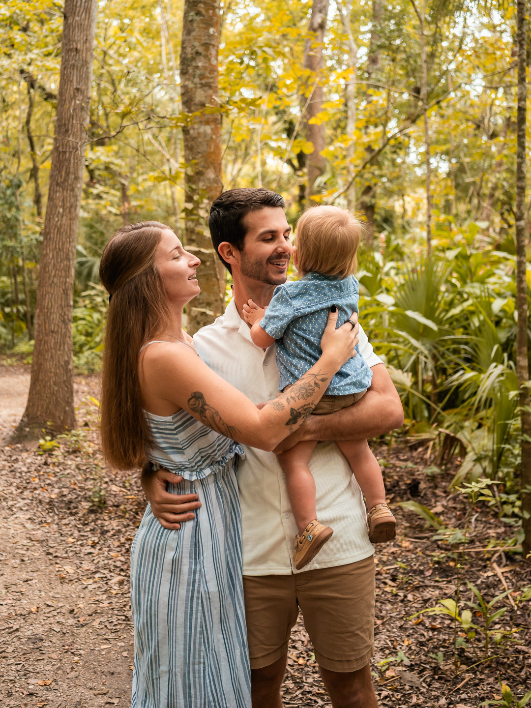 Parents holding their young son together among the trees during family photos in Port Orange.