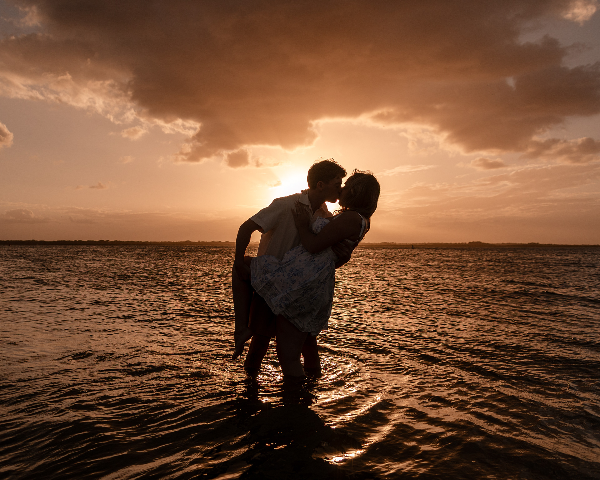 Romantic silhouette of a couple during sunset beach engagement session.