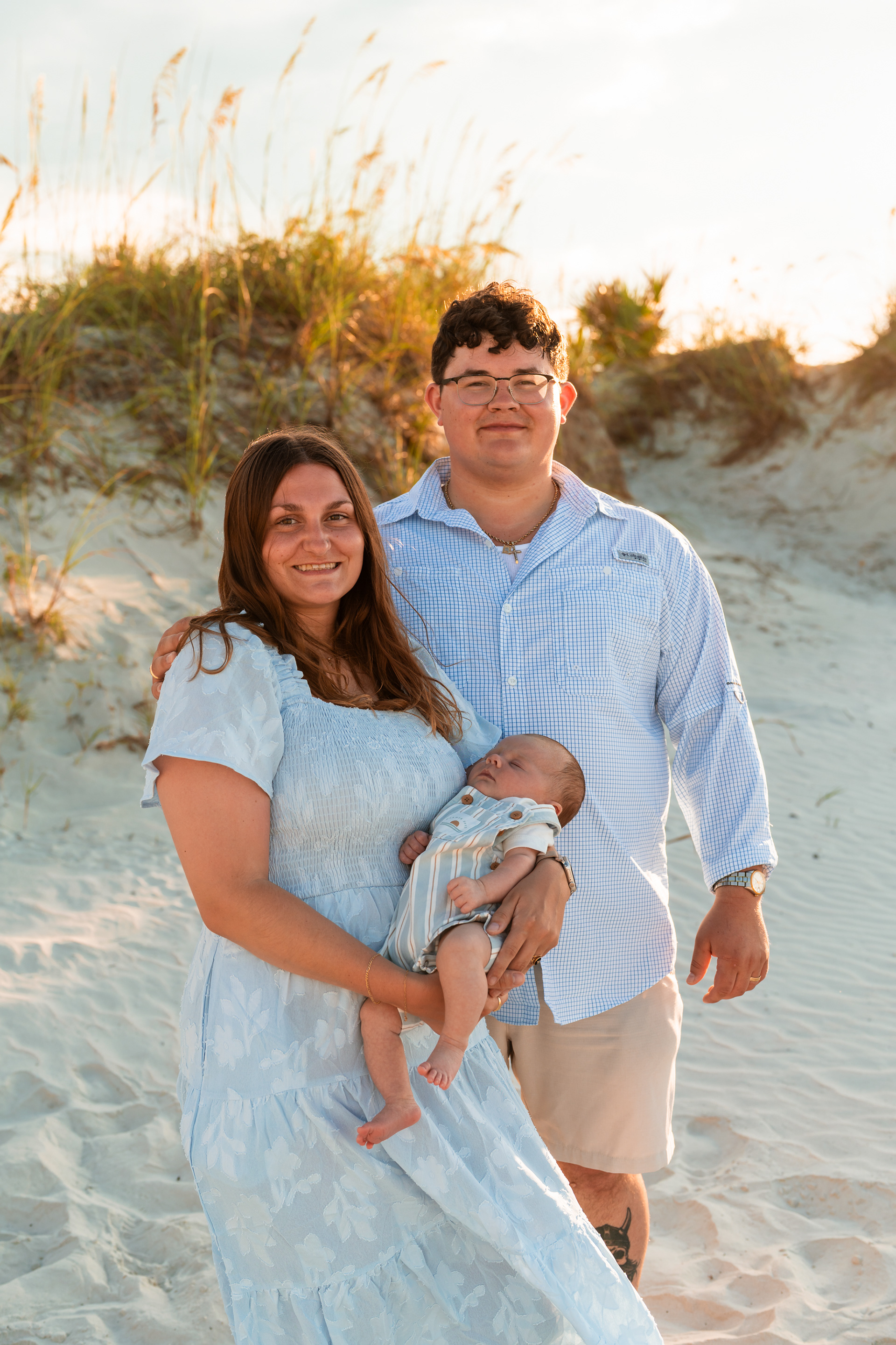 Parents holding their baby near the dunes during a Ponce Inlet beach family session.