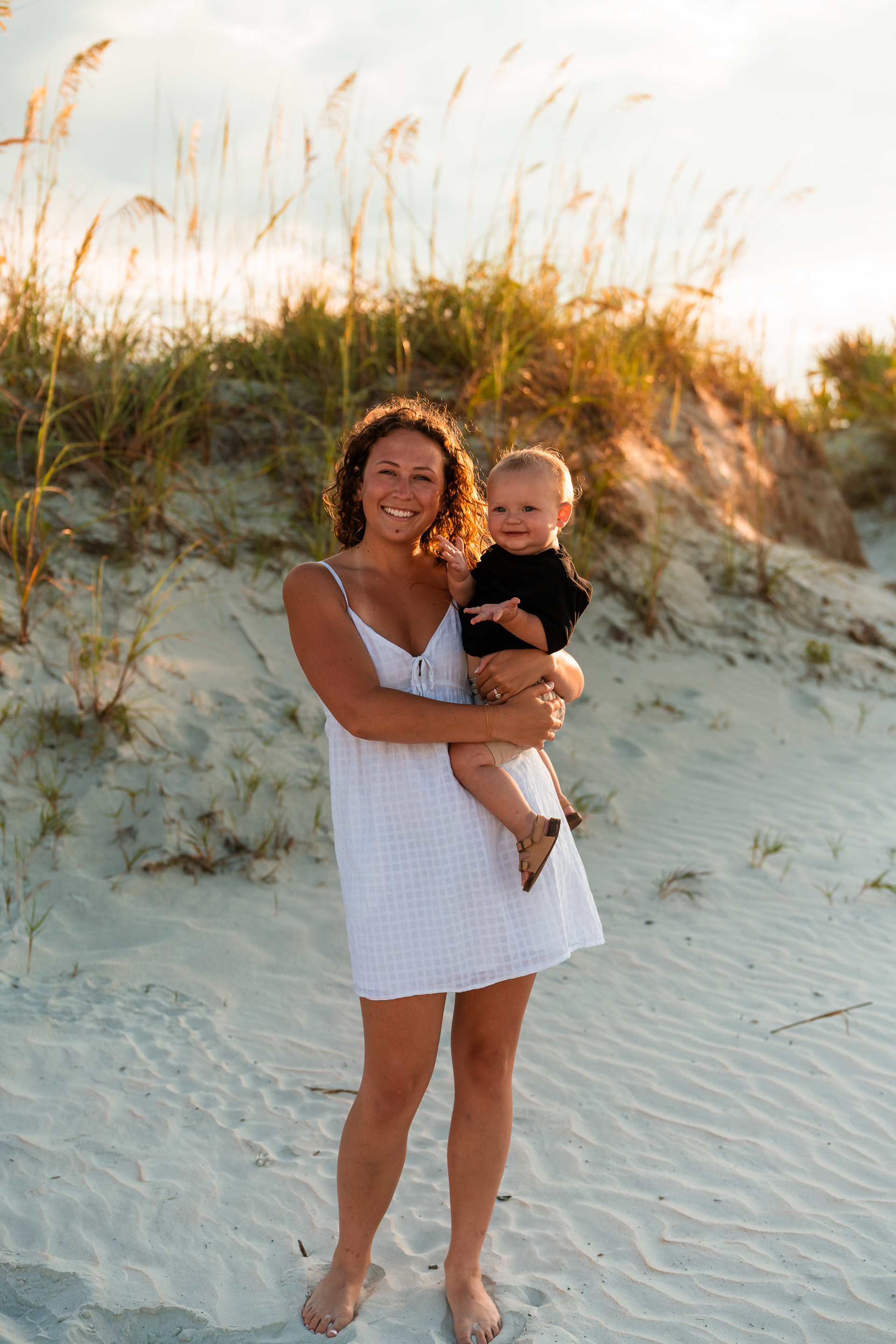 Woman holding a toddler in the dunes during a Ponce Inlet Jetty Beach photo session.