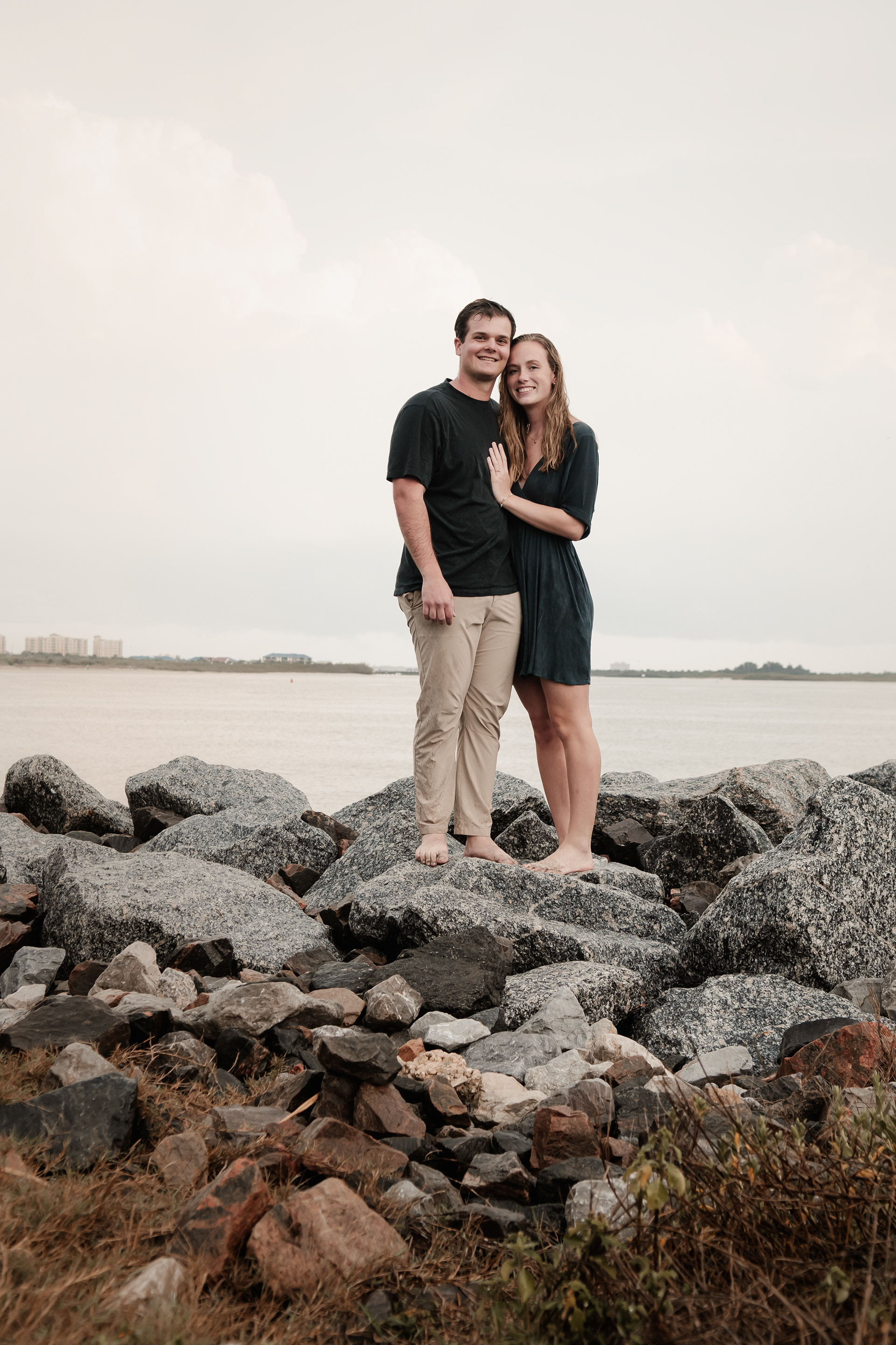 Ponce Inlet engagement portrait of couple standing together on rocks by the water