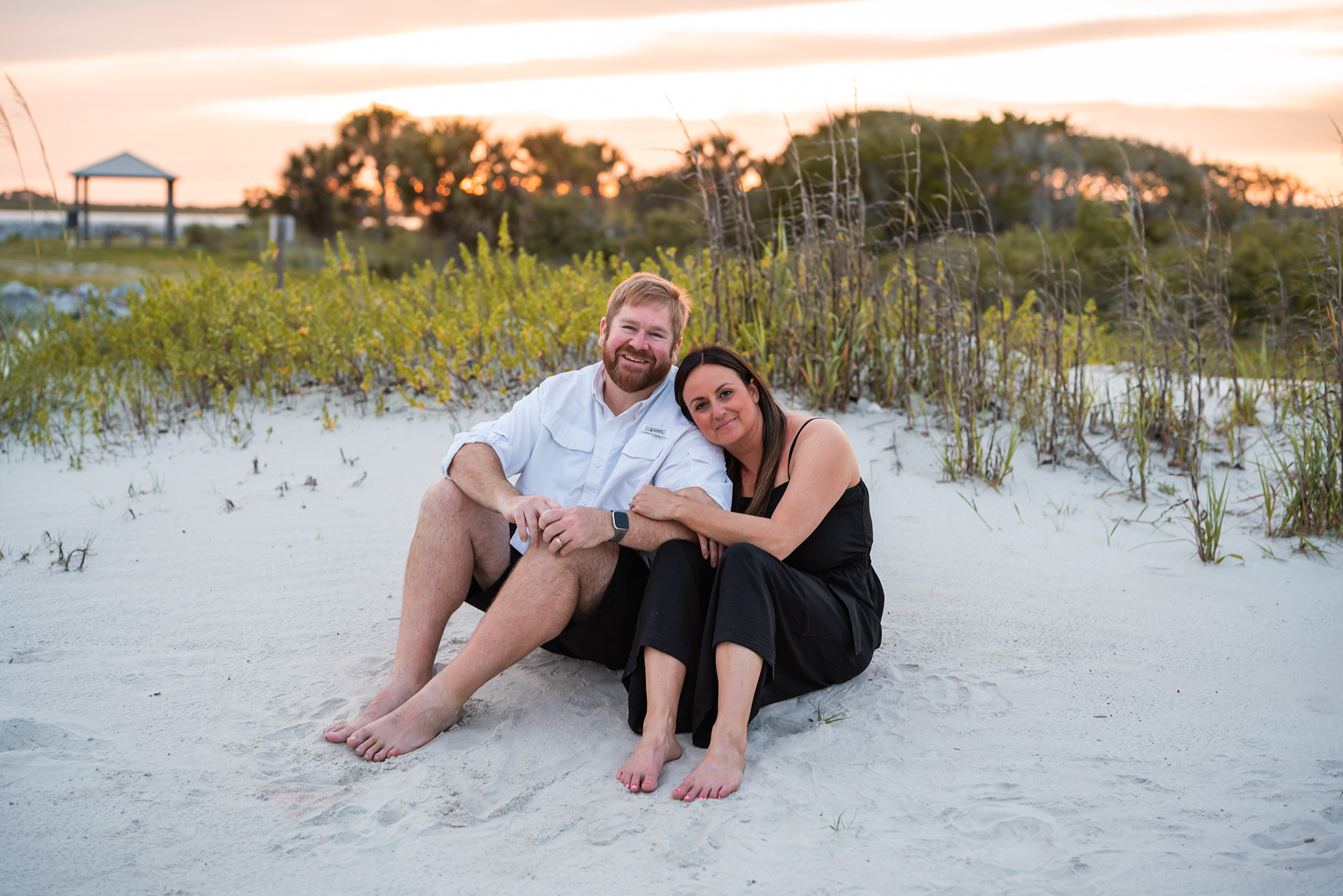 Couple sitting together in the sand during a family photography session at Ponce Inlet Beach.