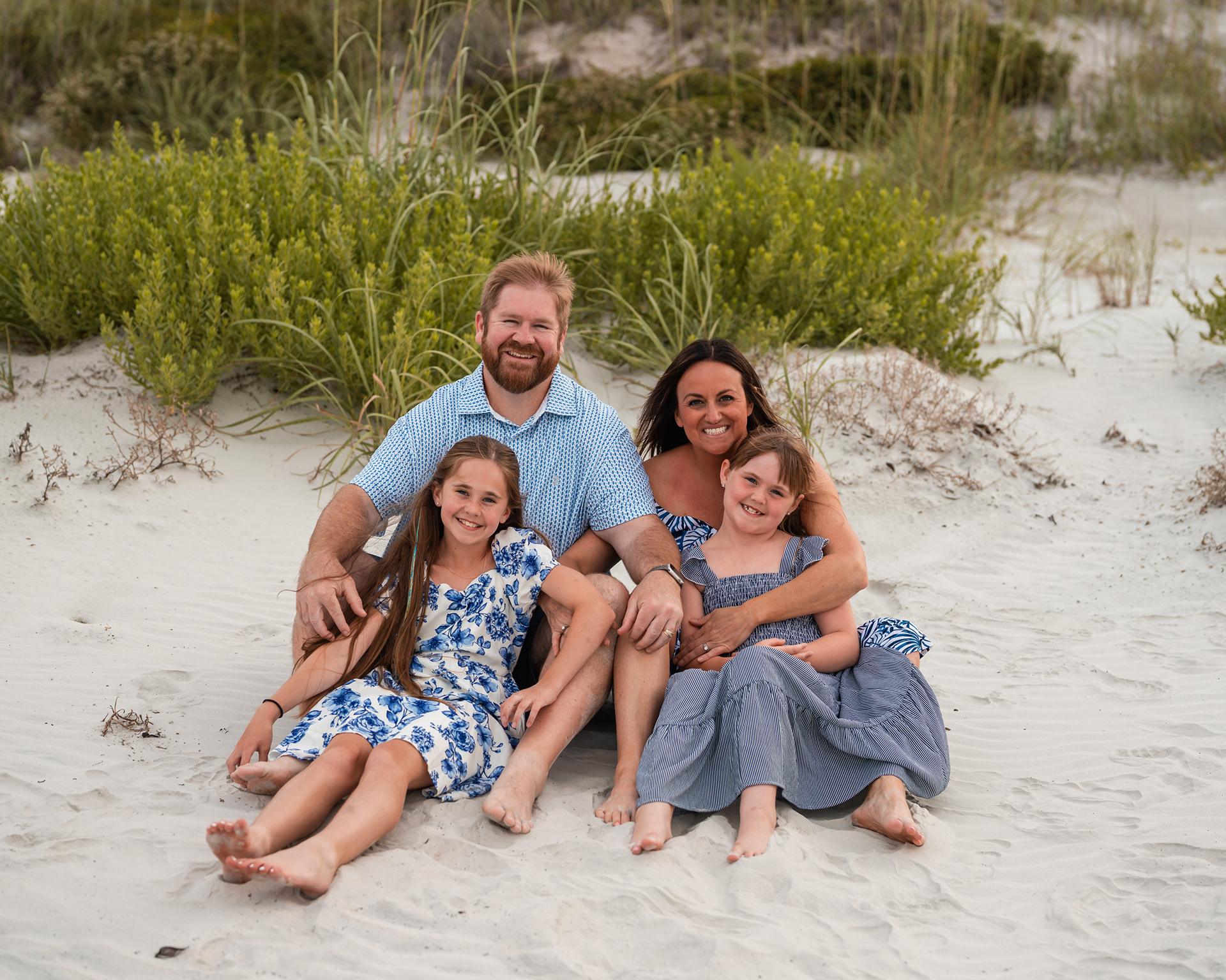 Family sitting in the sand near the dunes during a Ponce Inlet Beach family photography session.