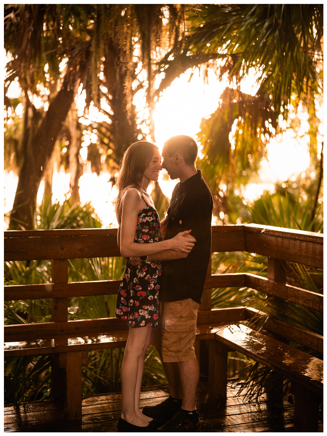 Couple kissing on a wet wooden footbridge at sunset at Washington Oaks Gardens State Park.