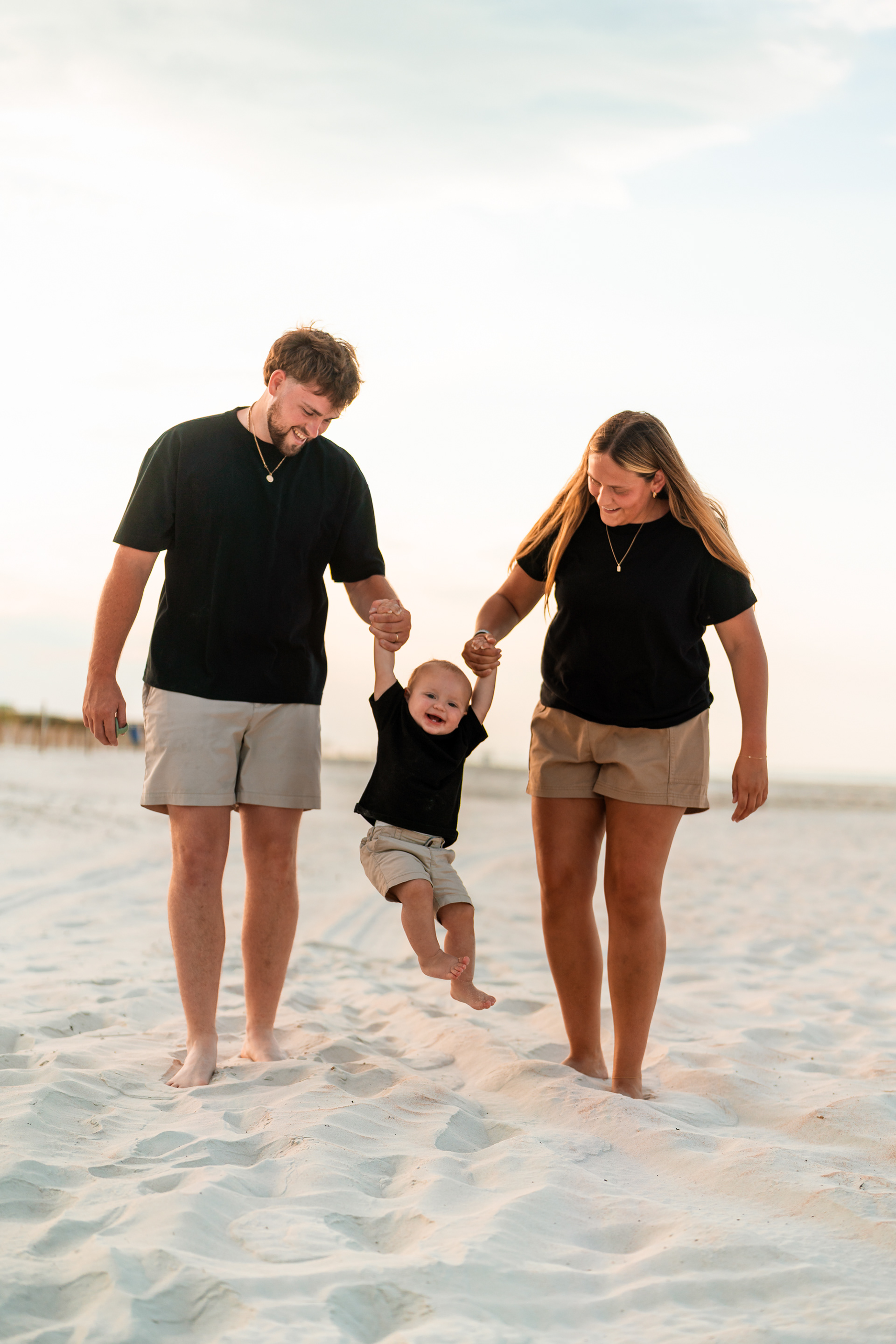 Parents walking with their child on the sand during a Ponce Inlet Beach family photo session.