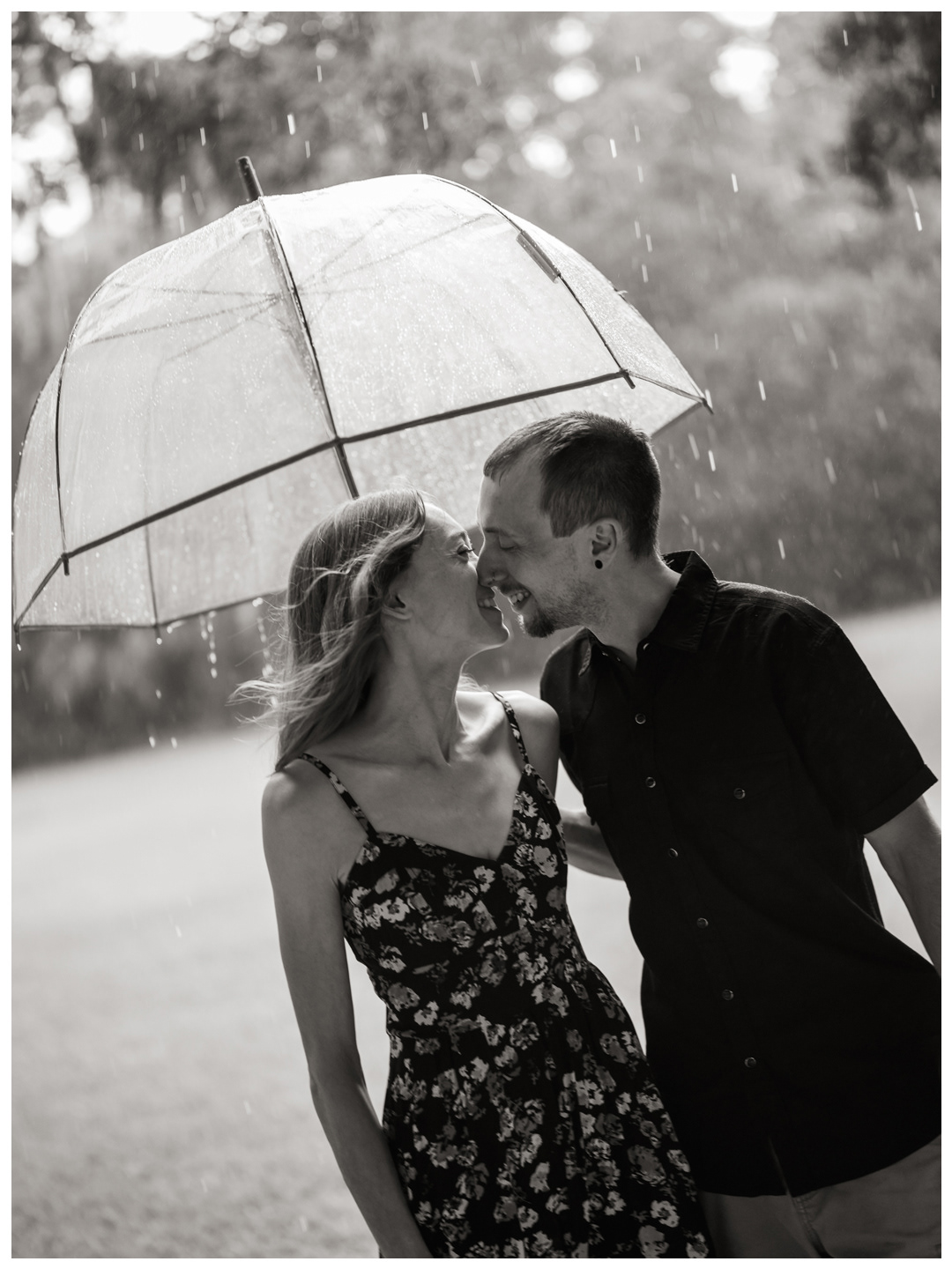 Black-and-white photo of a couple laughing under a clear umbrella in the rain at Washington Oaks Gardens State Park.