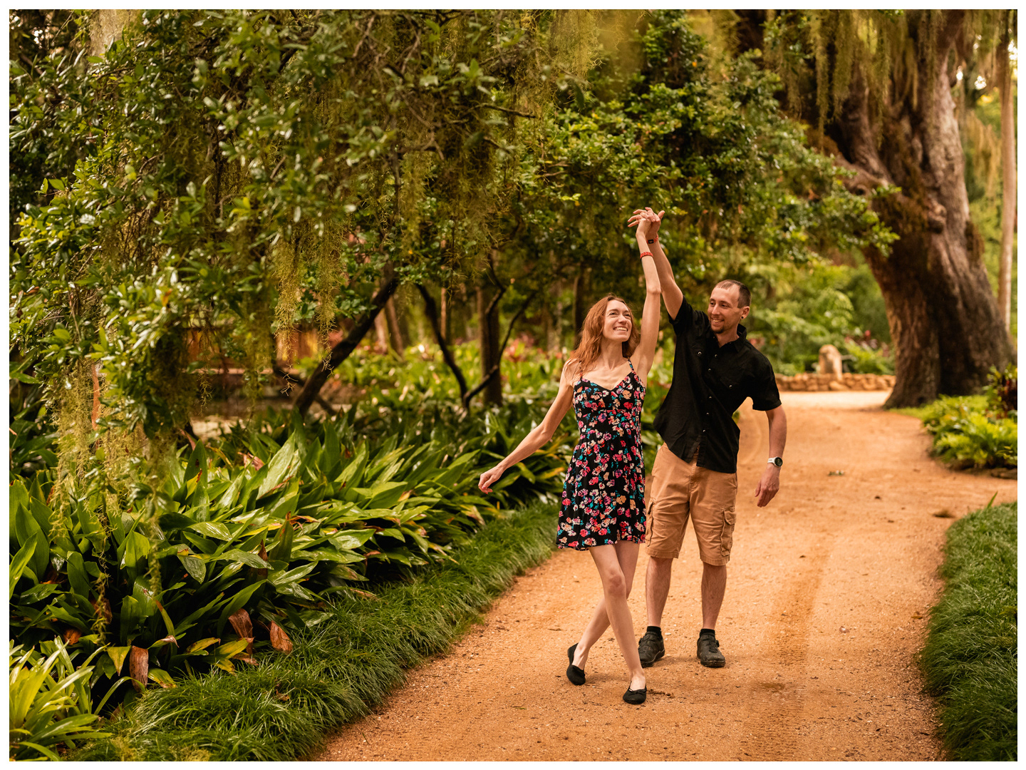 Couple walking hand in hand along a garden path during a Washington Oaks couples photo session.