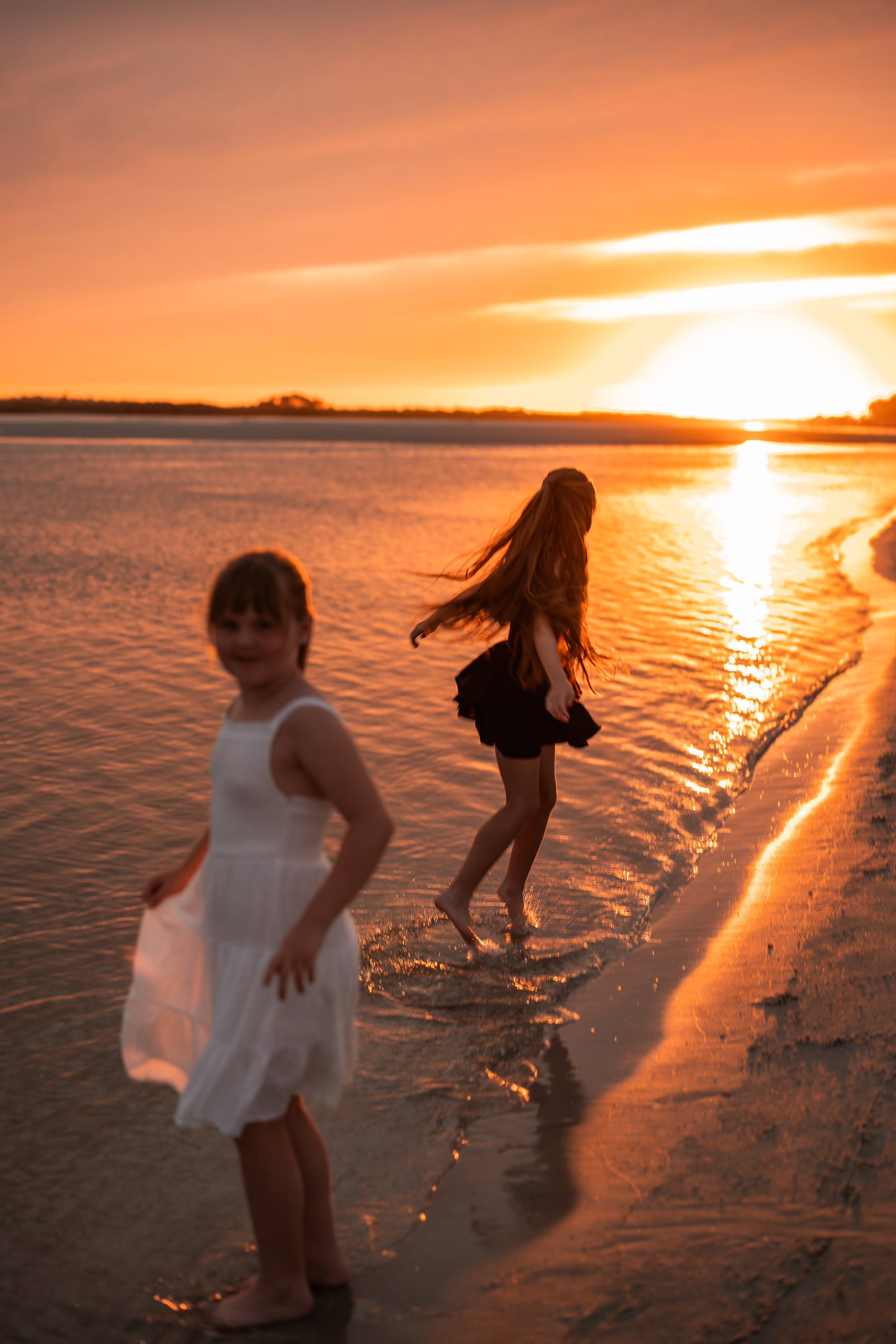 Two girls playing along the water at sunset during a Ponce Inlet Beach family photo session.