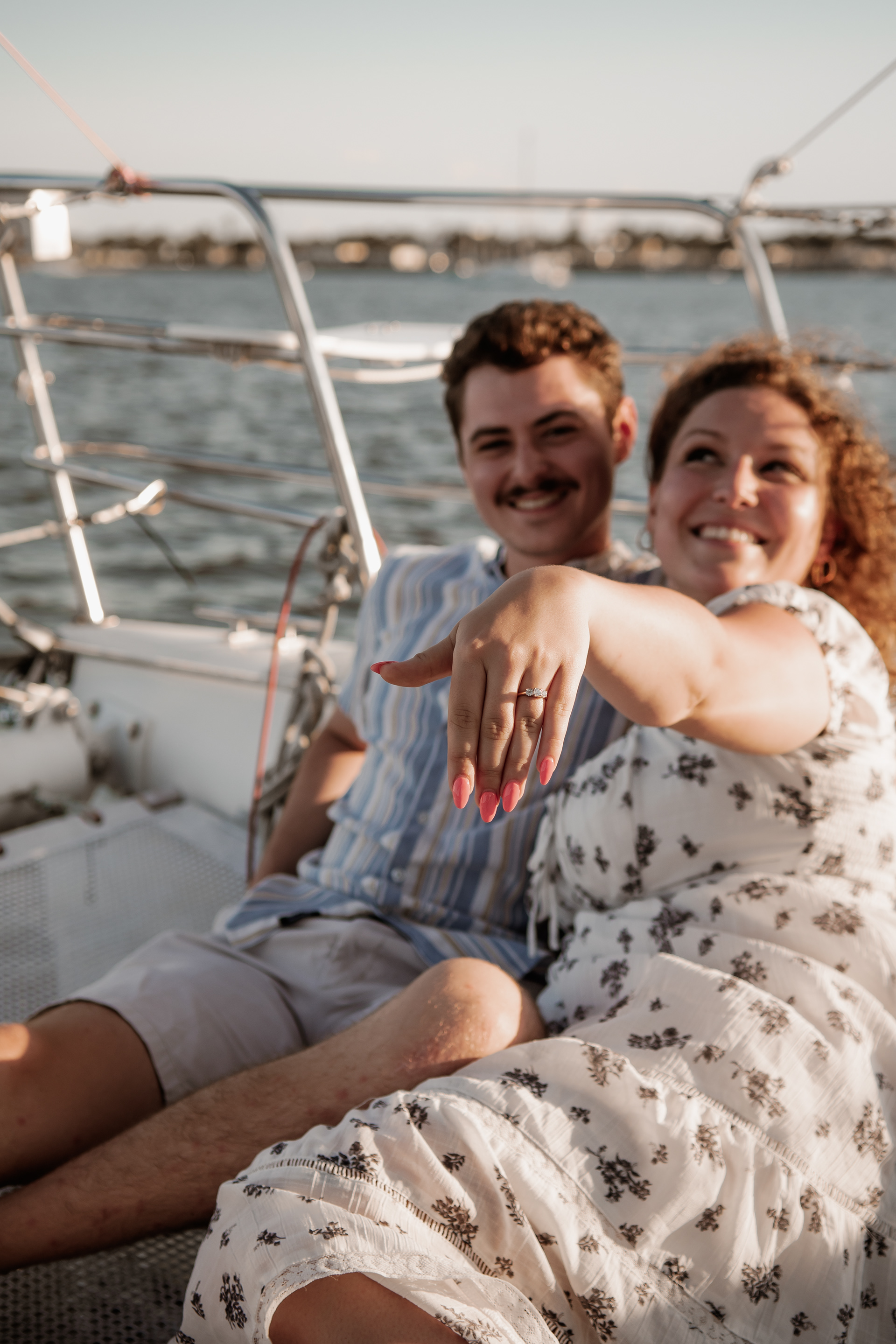 Daytona Beach engagement photo with couple on sailboat and bride-to-be showing ring