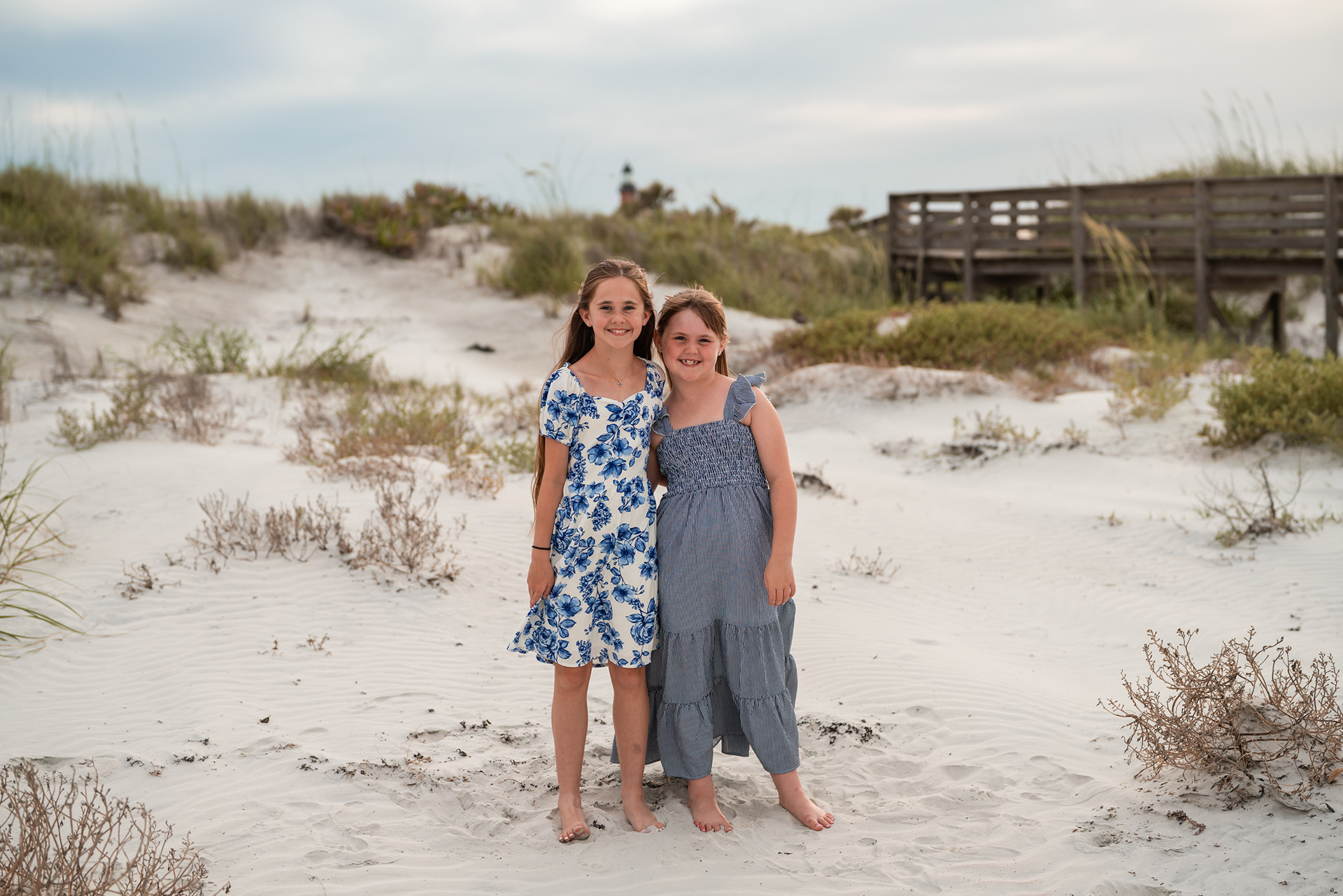 Sisters standing in the dunes during a beach photography session in Ponce Inlet, Florida.