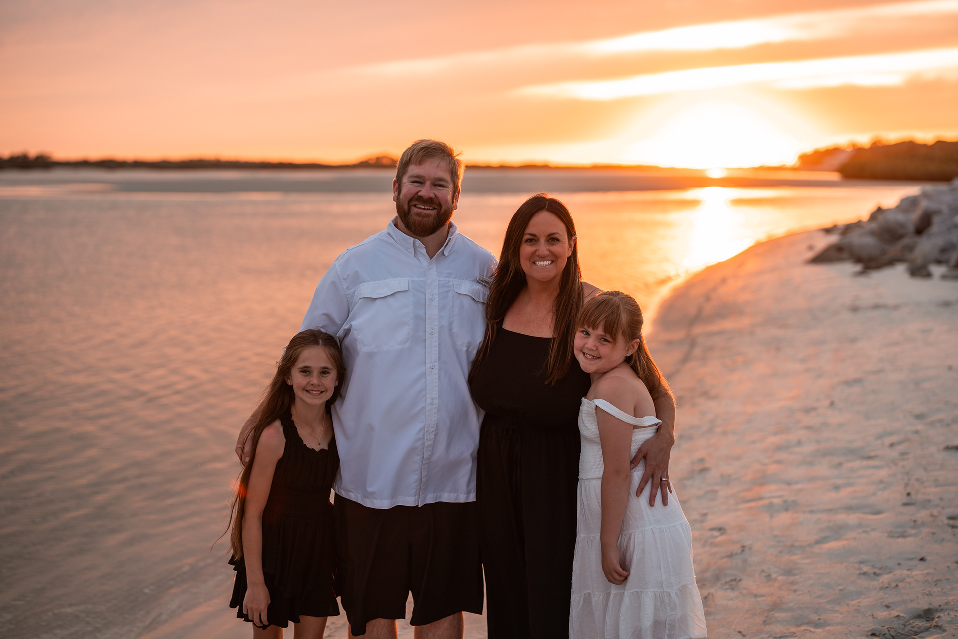 Family standing by the water during a Ponce Inlet Beach sunset photography session.