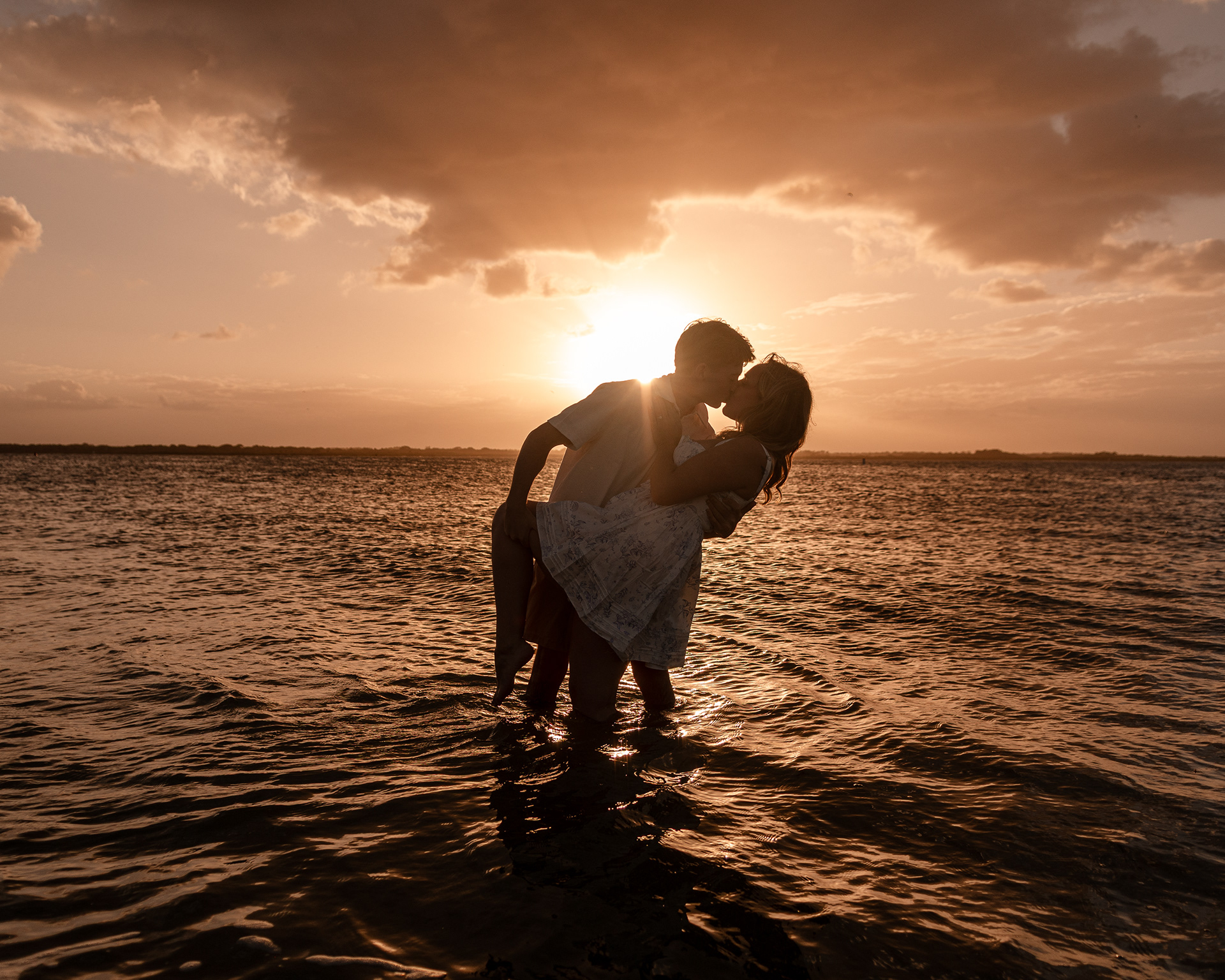 Joey and Lexi sharing a sunset moment in the water after their beach proposal in New Smyrna Beach.