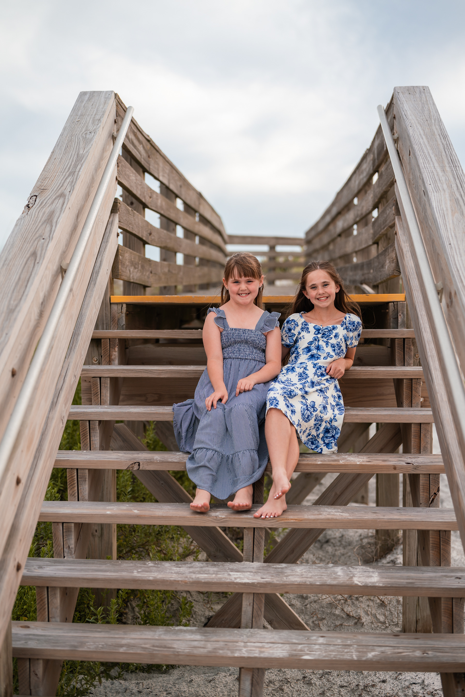 Two girls sitting on the beach access stairs during a family photography session in Ponce Inlet.