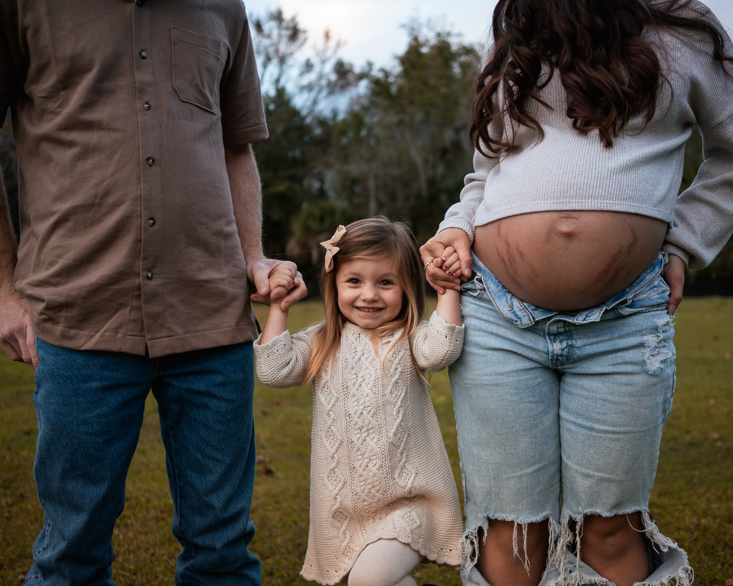 Family maternity photo with child standing between expecting parents