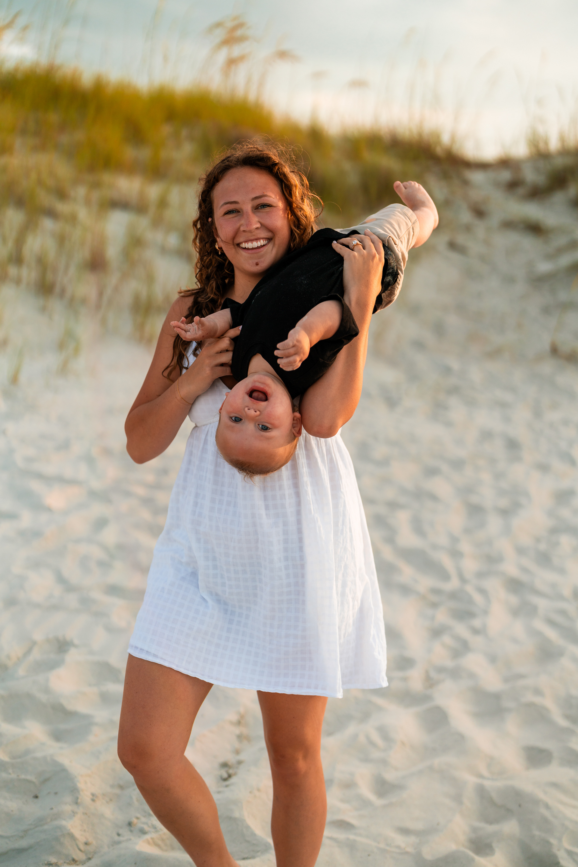 Woman playing with a toddler in the sand during a family photo session at Ponce Inlet Jetty Beach.