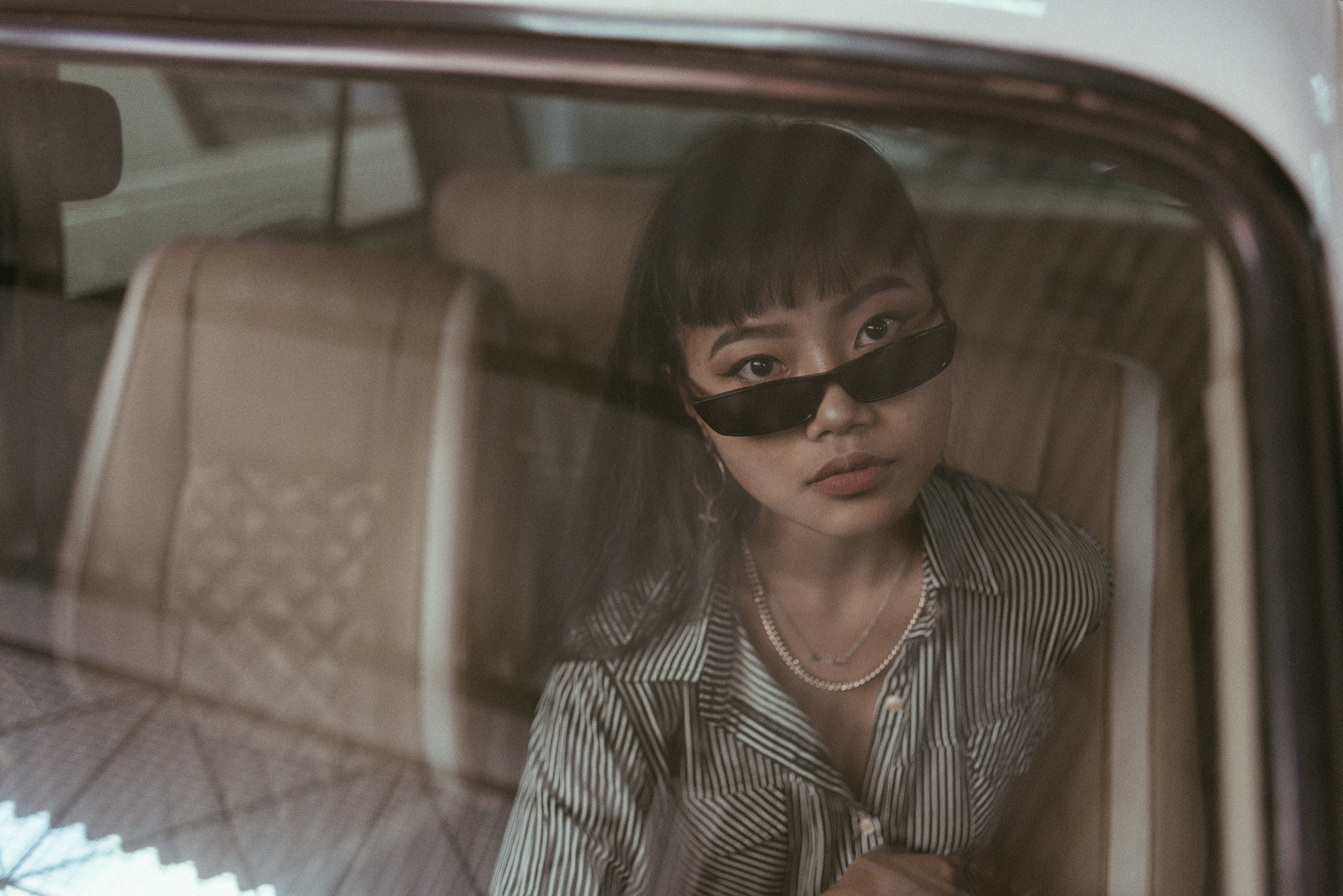 "Mysterious retro-themed image featuring a contemplative modern woman in a car, evoking a sense of nostalgia and introspection."