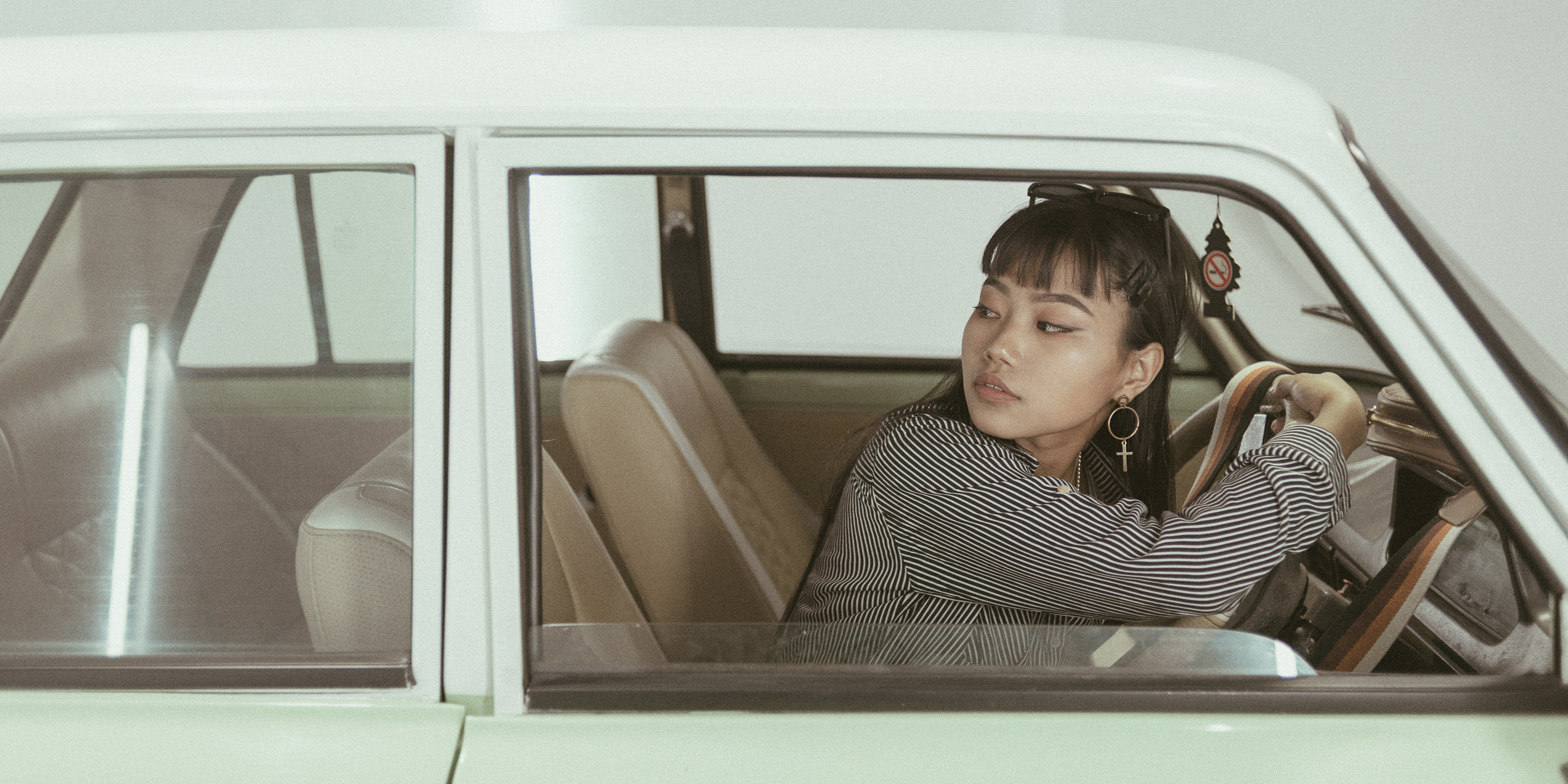 "Mysterious retro-themed image featuring a contemplative modern woman in a car, evoking a sense of nostalgia and introspection."