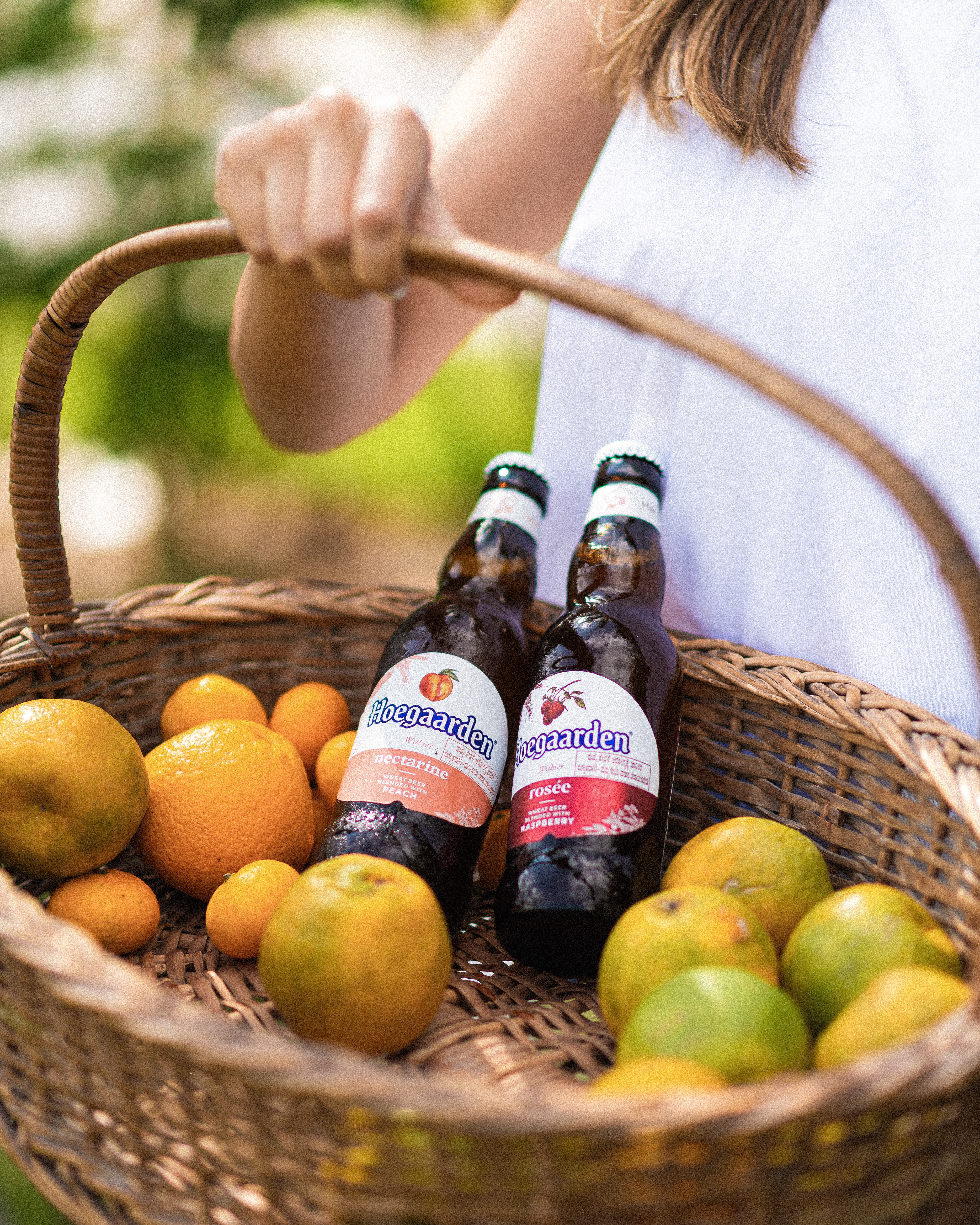 "Hoegaarden beer bottle surrounded by vibrant oranges in a serene natural setting, blending refreshing citrus flavors with the crispness of nature."