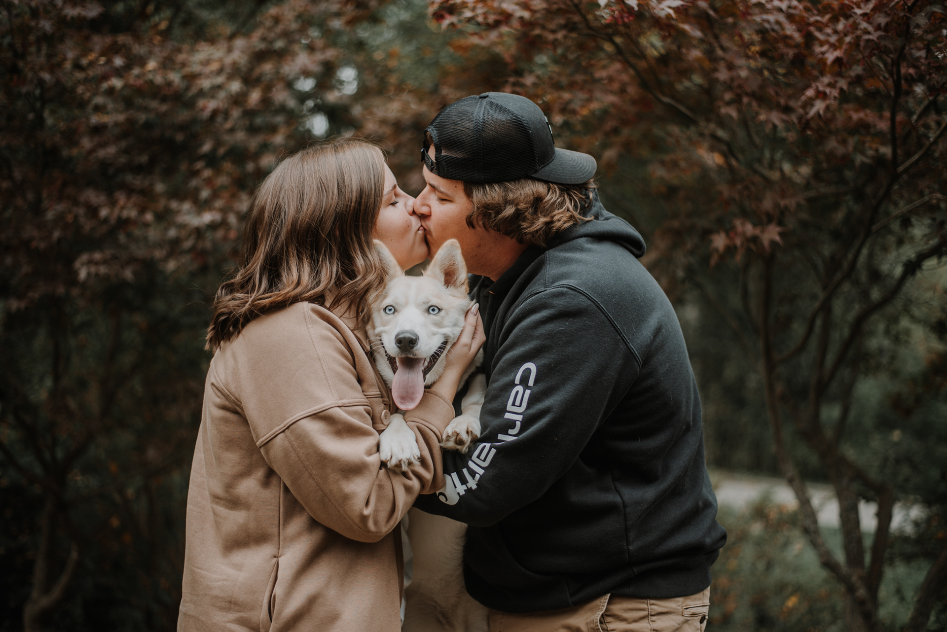 A & J kissing with dog in the middle.