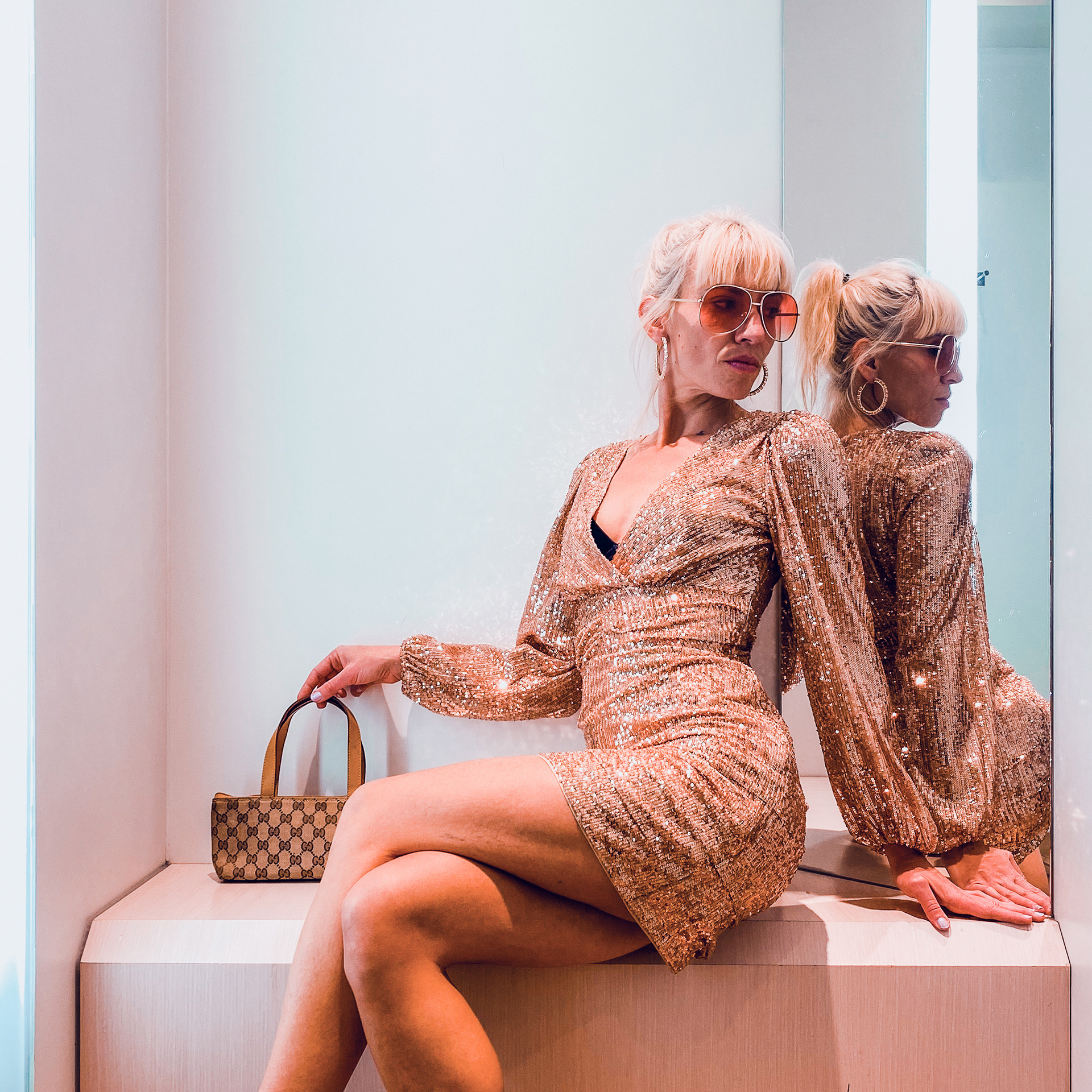 Influenceuse posant dans une robe à paillettes avec un sac de luxe
