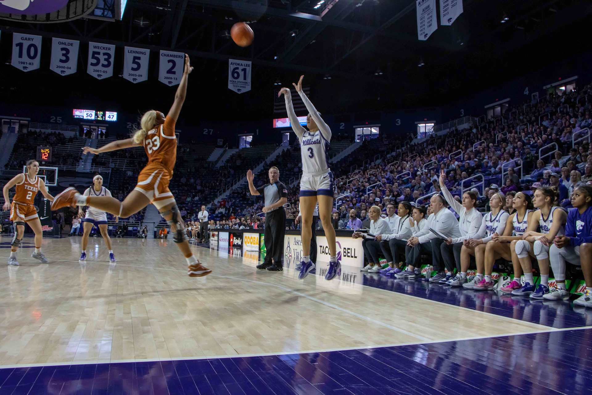 Guard Jaelyn Glenn shoots a 3 as Texas forward Aaliyah Moore runs to her in a block attempt. Although the shot missed, center Ayoka Lee rebounded and went up for two, increasing K-State's lead 52-47 with 6:20 left in the fourth quarter.