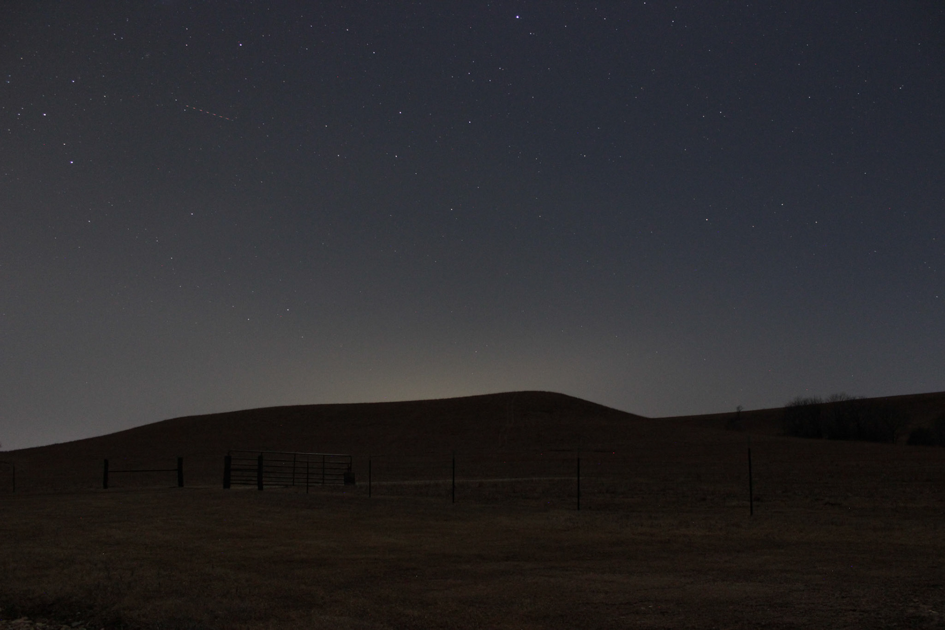 Looking out over one of the shallow pasture hills, the stars shone much brighter than over the city. A plane can be seen streaking across the star-studded sky.