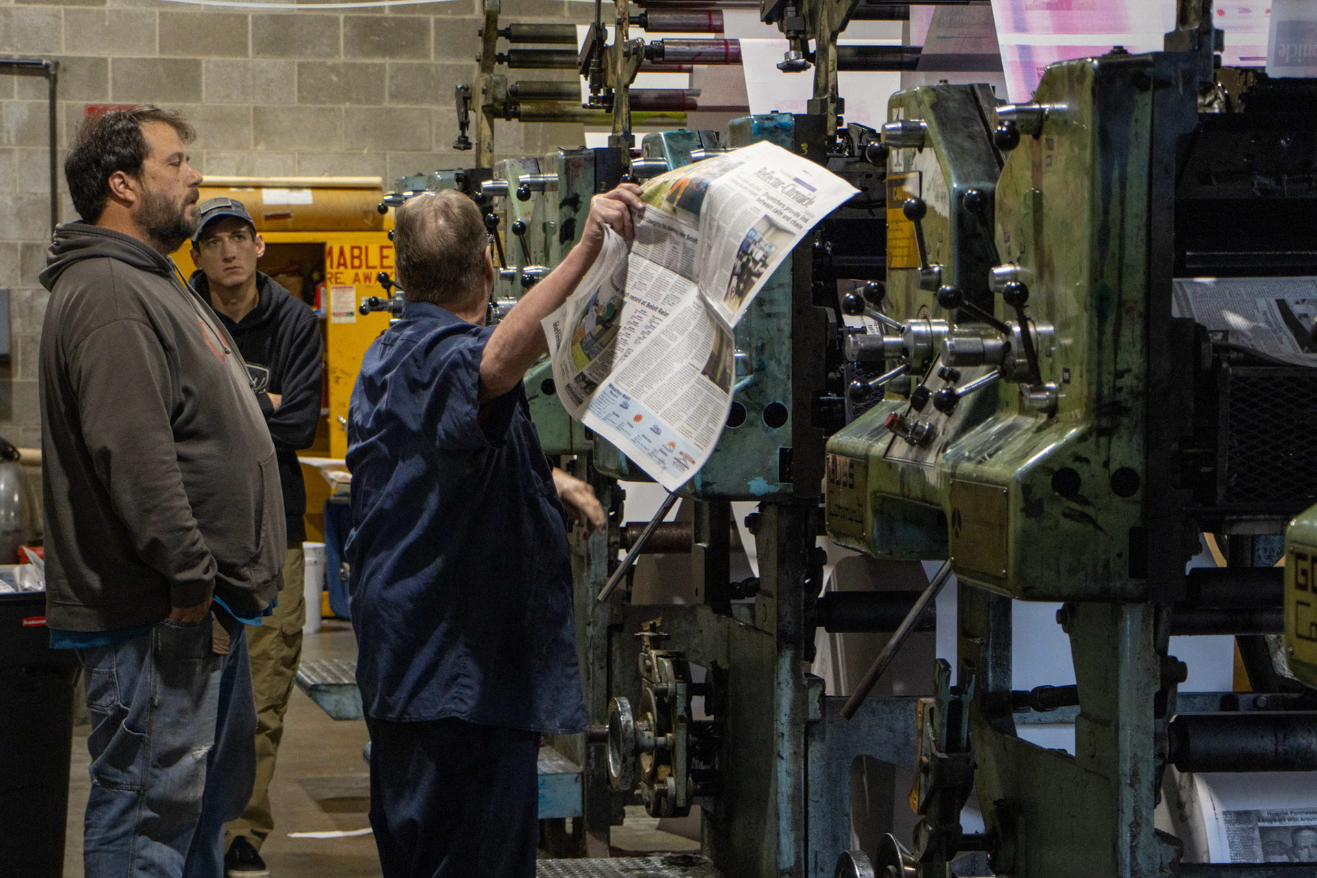 Pressman Grady Malsbury speaks with production manager Landon Obee and production assistant Brandon Dobbs about their second printing press — a Goss Community press from Clay Center, Kansas.