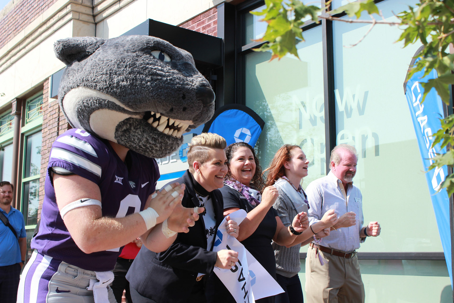 Willie, Kiley Sidman, associate market director at JPMorgan Chase & Co., Carrie Rowe, Chase’s Manhattan branch manager, associate banker Caitlyn Cordell and Mayor Mark Hatesohl Wabash with a partial Kansas State Marching Band at Chase's Manhattan branch opening. The branch officially opened on Aug. 29, and Chase made two donations to local nonprofits in celebration. (Featured in the Collegian)