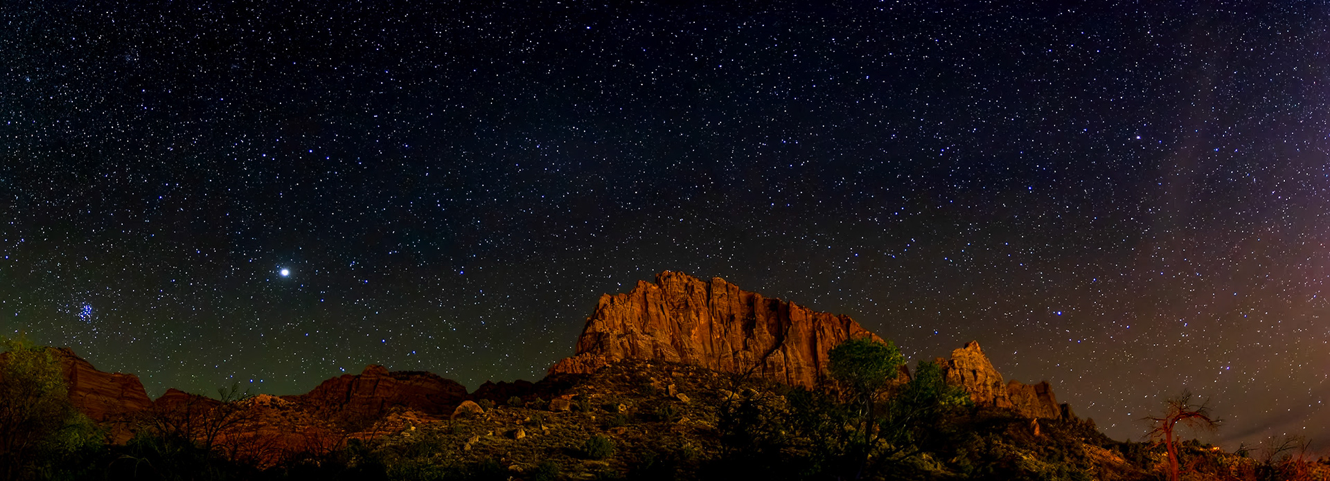 Panarama of the night sky over The Watchman in Zion National Park as seen from the Watchman Campground