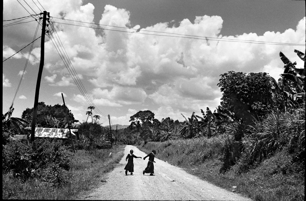 Two girls return from school along the villages main dirt road