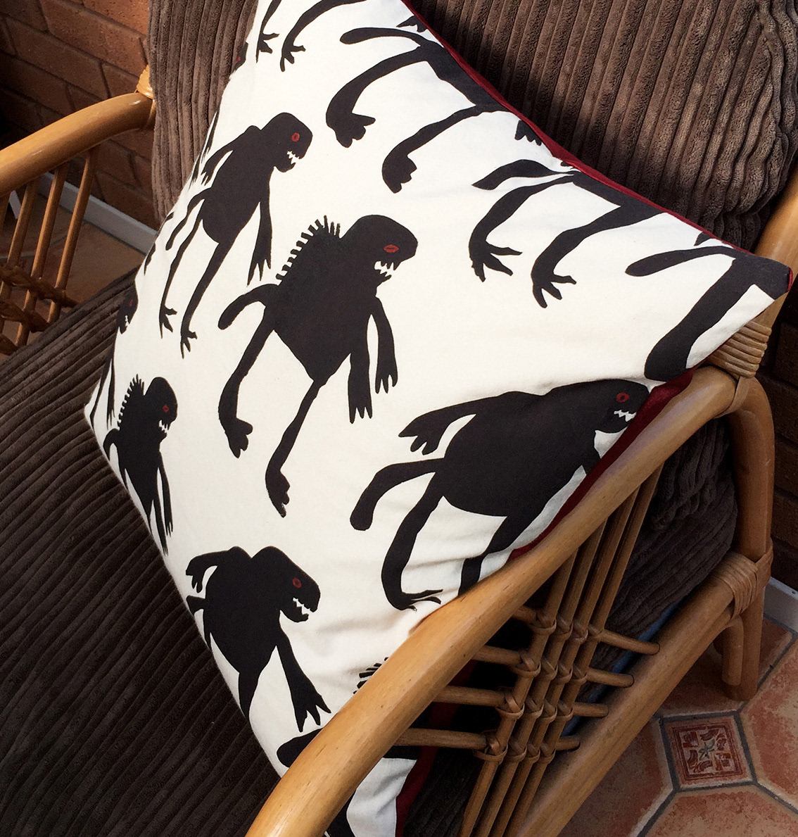 Photo of a dinosaur cushion featuring a printed textile design and red satin reverse.