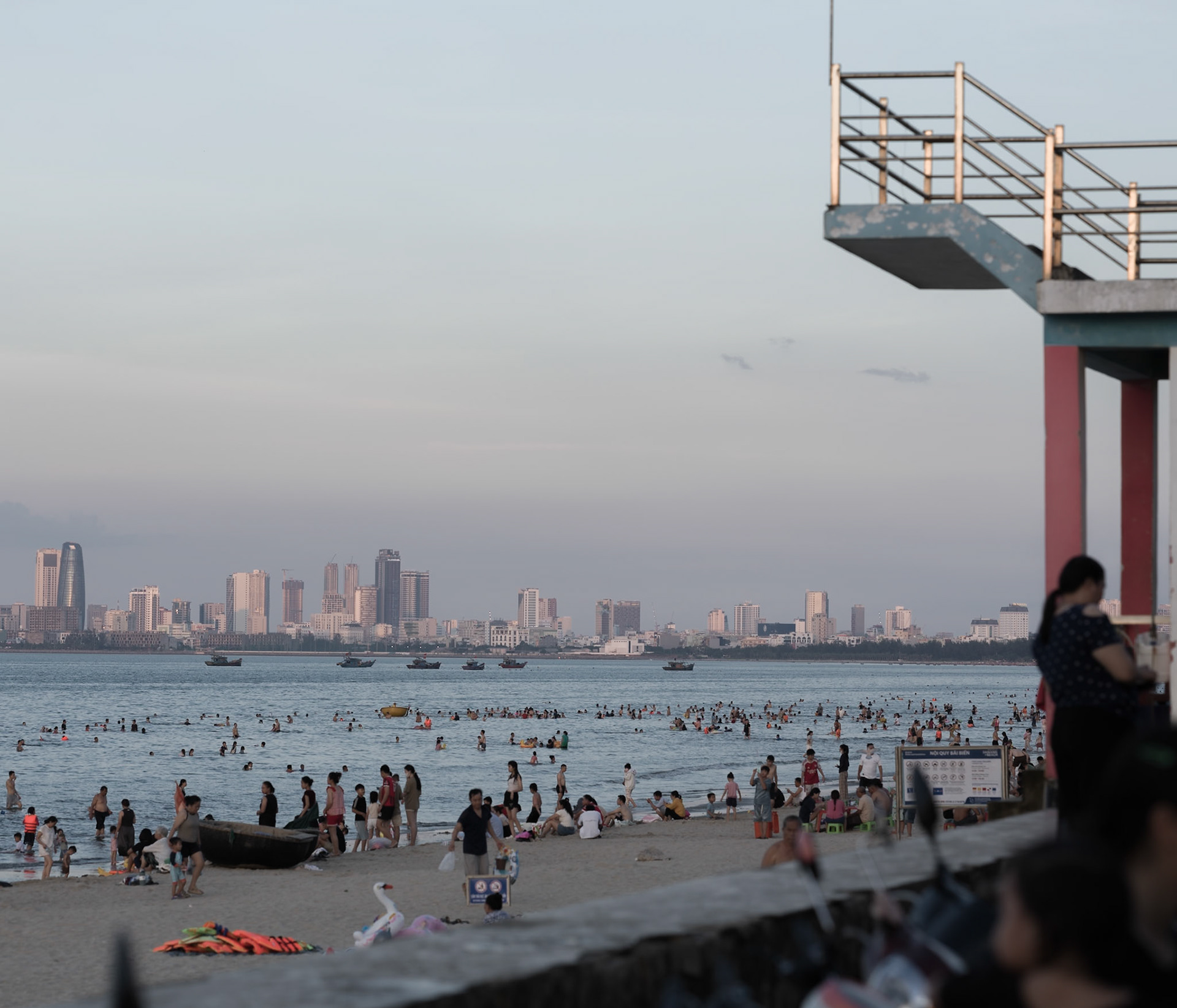 People at the beach in Thanh Khê with the skyline of Đà Nẵng across the bay., Đà Nẵng Bay, Jun. 2026
