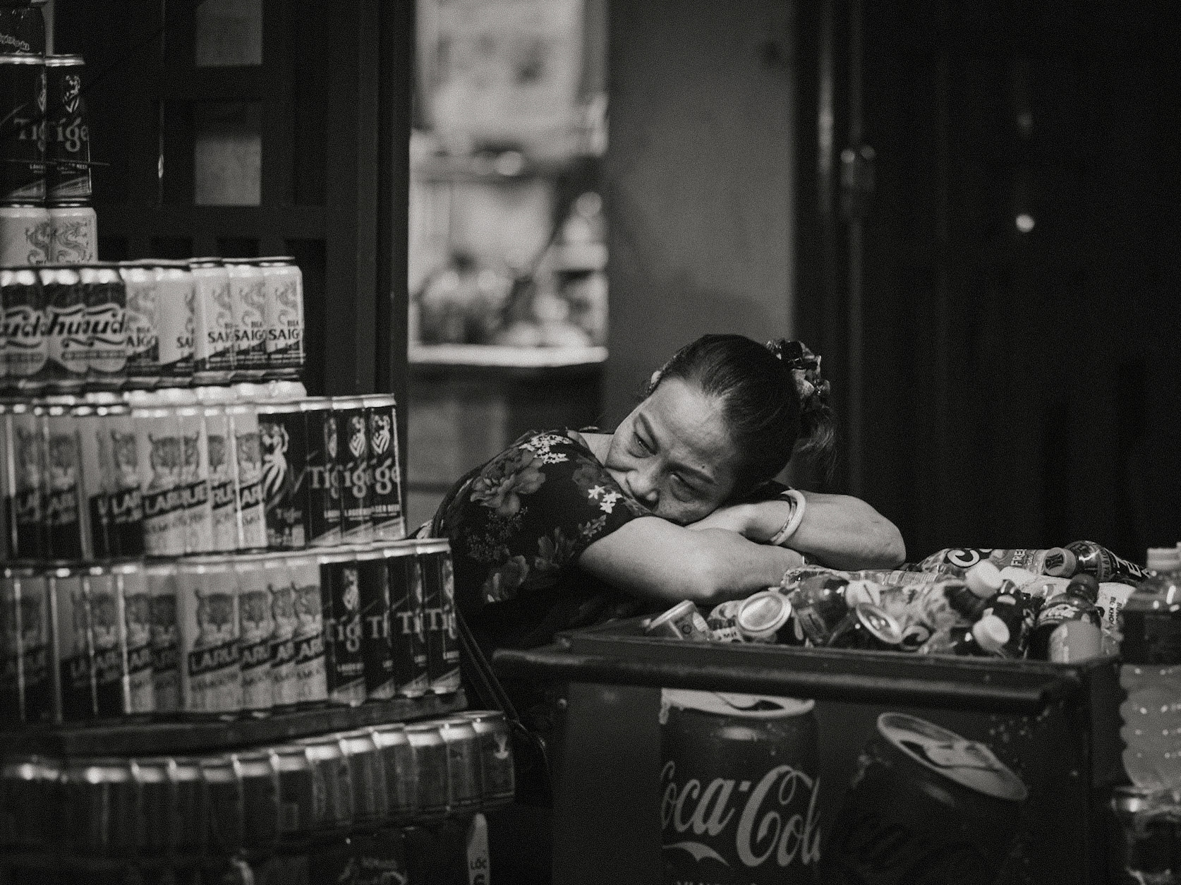 A street vendor in Hoi An taking a quiet moment of rest after a long, hot day selling cold drinks.                     Part of the VN25 black-and-white series. All rights reserved.