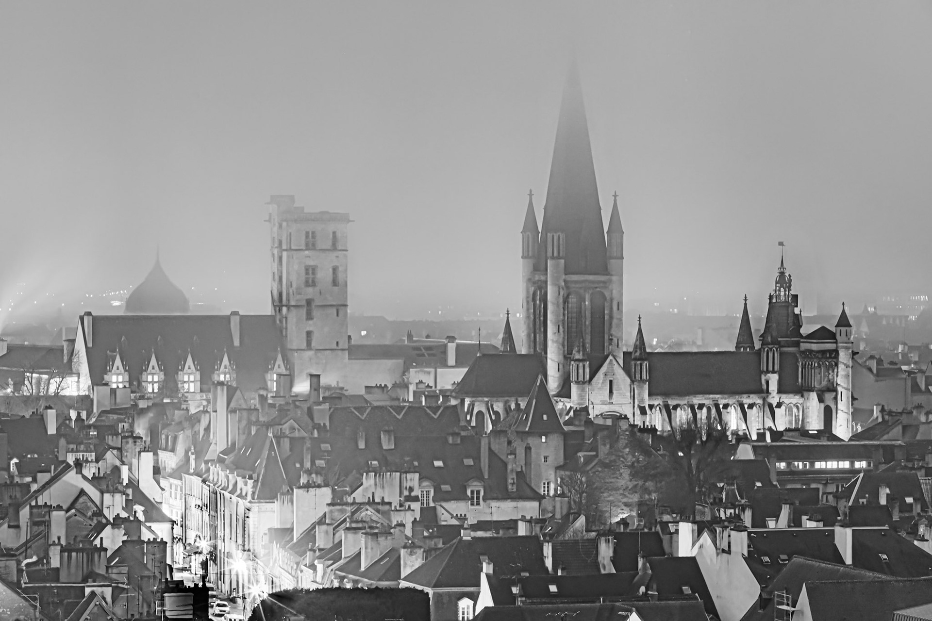 Vue aérienne de Dijon en noir et blanc, dans le brouillard, sur la tour Philippe Le Bon, le clocher  de l'église Notre-Dame et la coupole du musée d'art sacré.